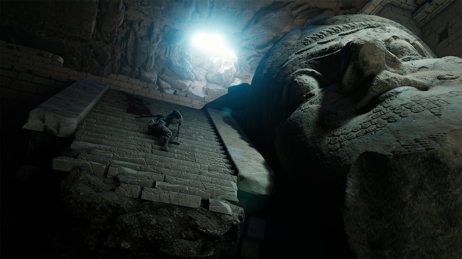 Man climbing stairs near giant statue in cave HD Wallpaper