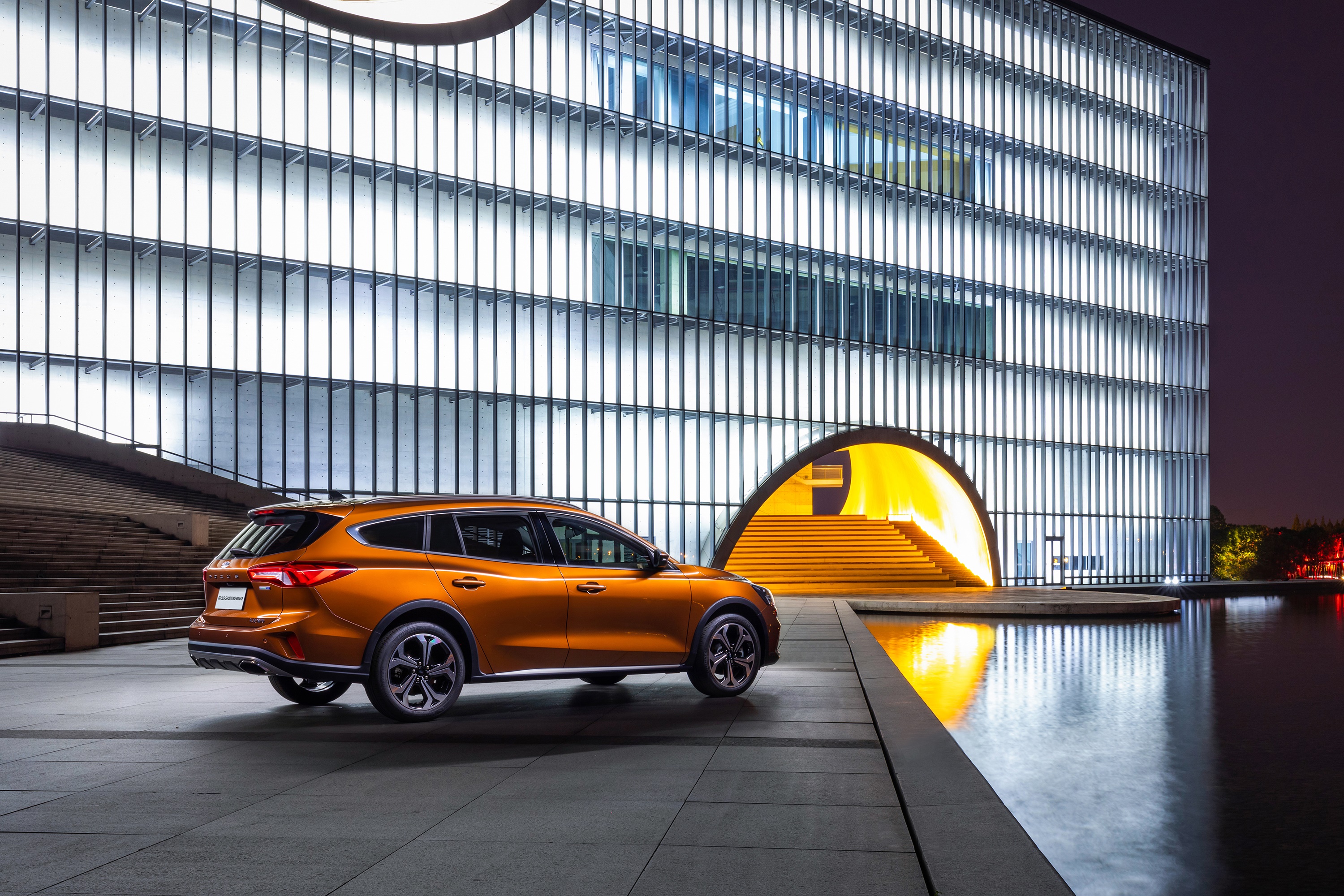 Orange Ford Focus Shooting Brake parked by modern building HD Wallpaper