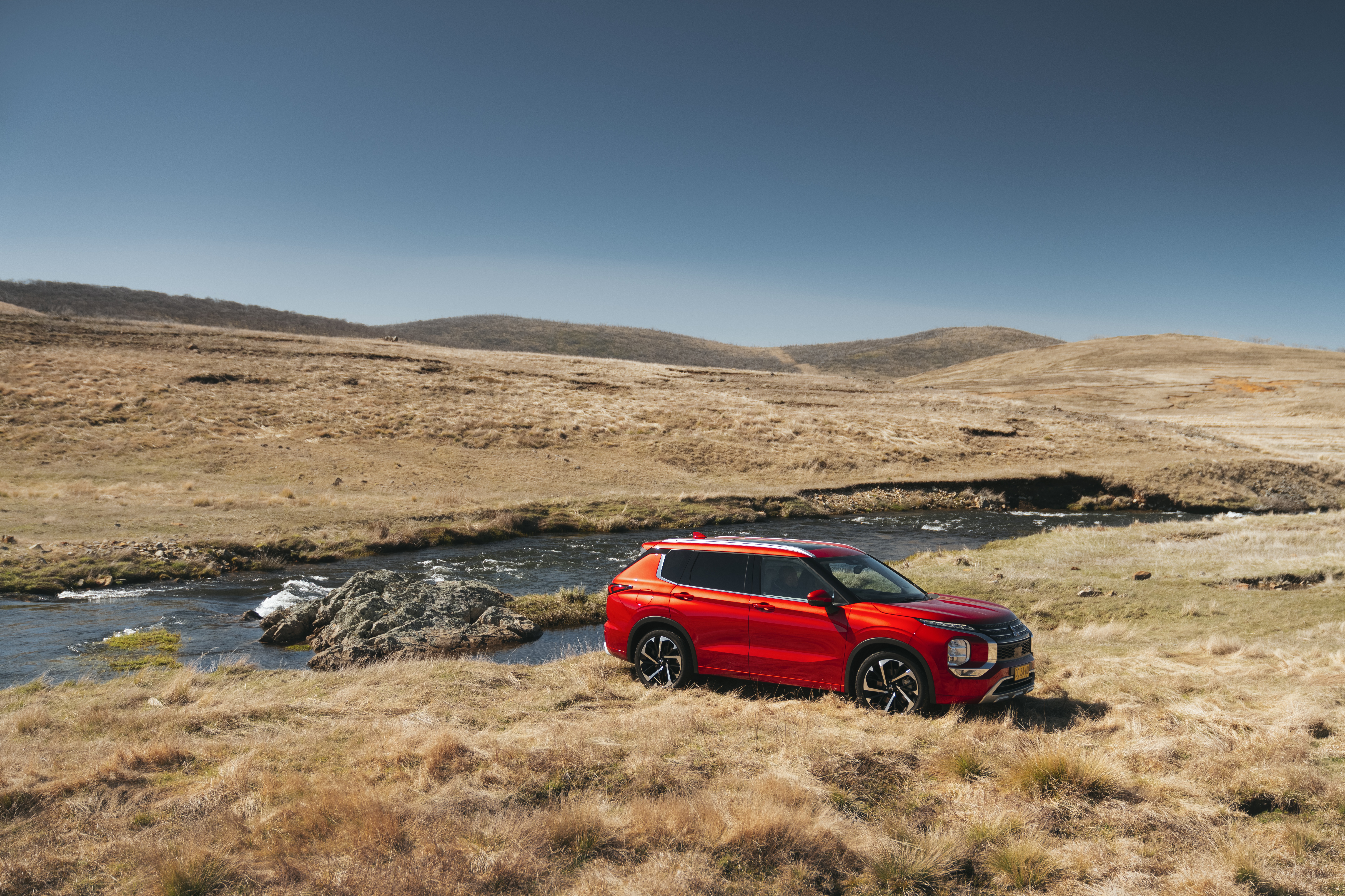 Red Mitsubishi Outlander SUV parked by a stream HD Wallpaper