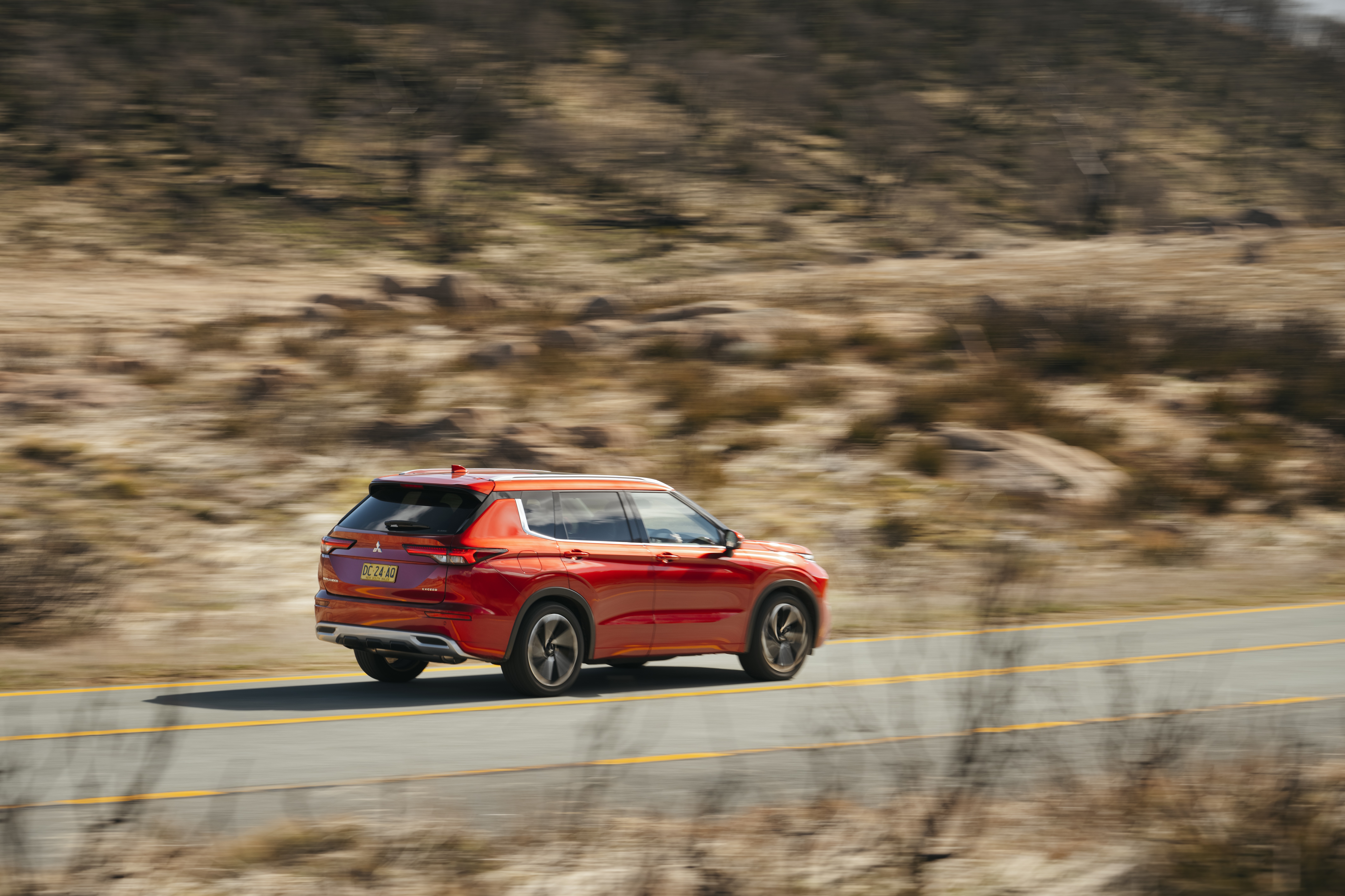 Red Mitsubishi Outlander driving on a road HD Wallpaper