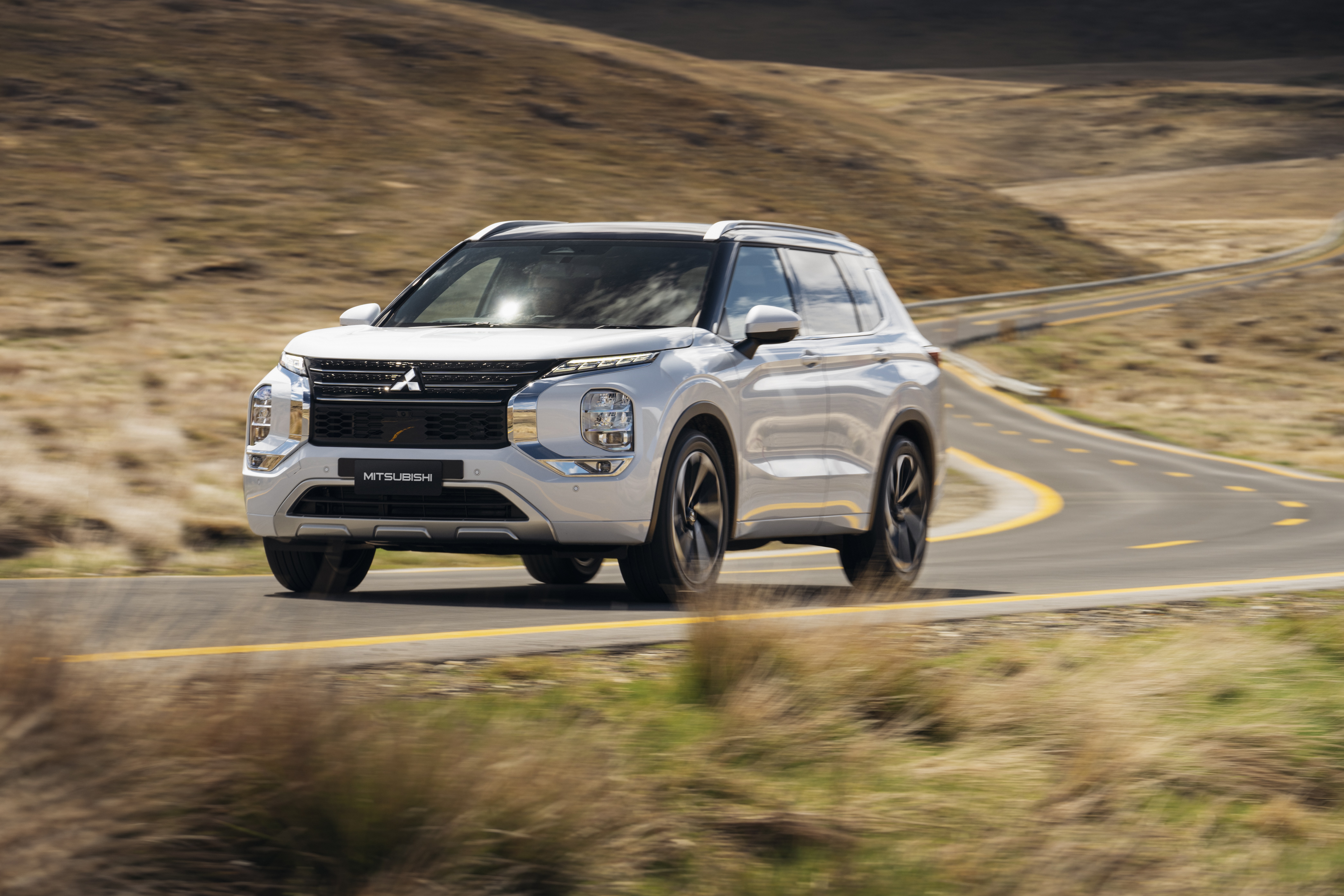 White Mitsubishi Outlander driving on a winding road HD Wallpaper