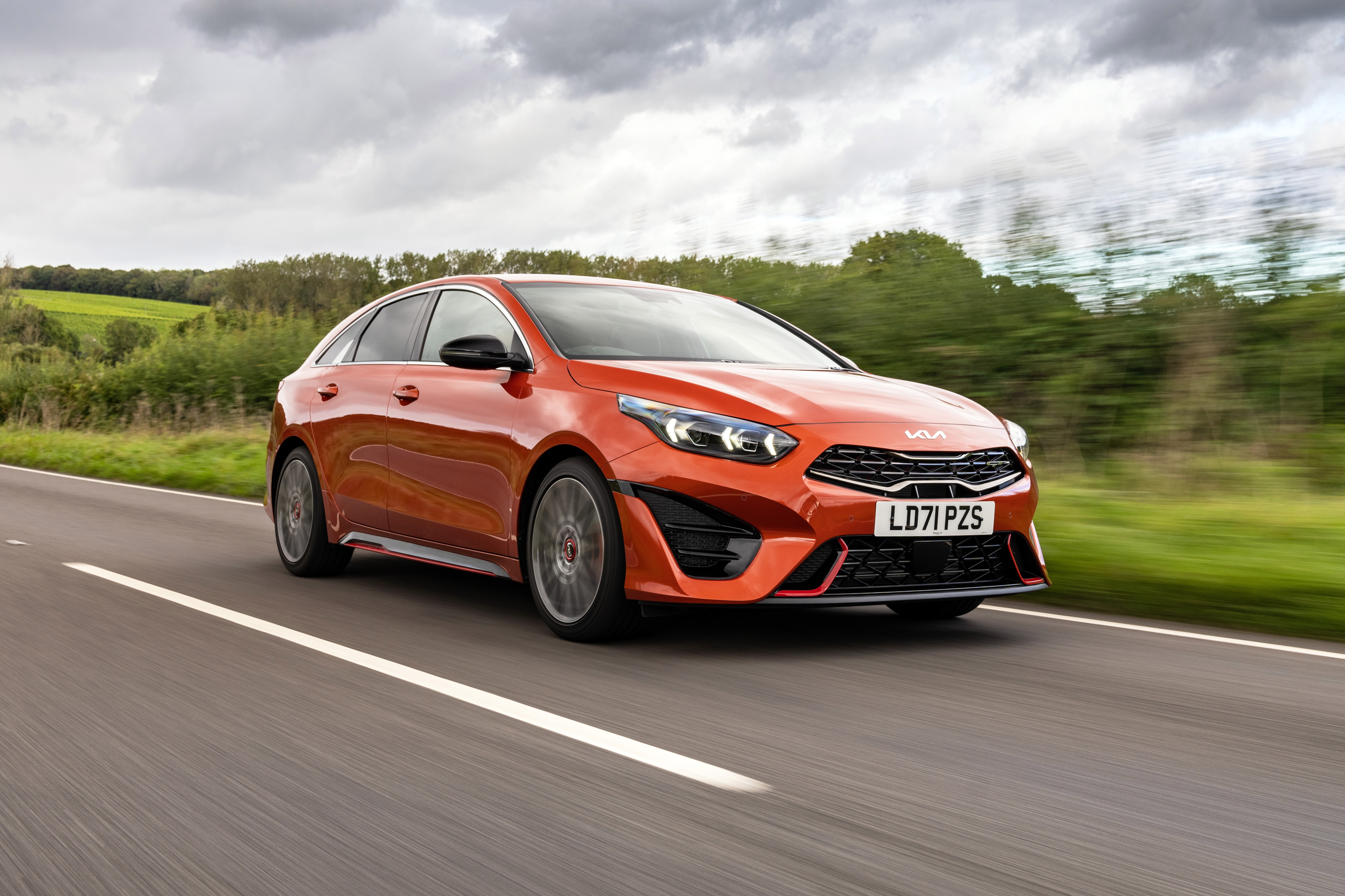 Orange Kia ProCeed GT driving on a road HD Wallpaper
