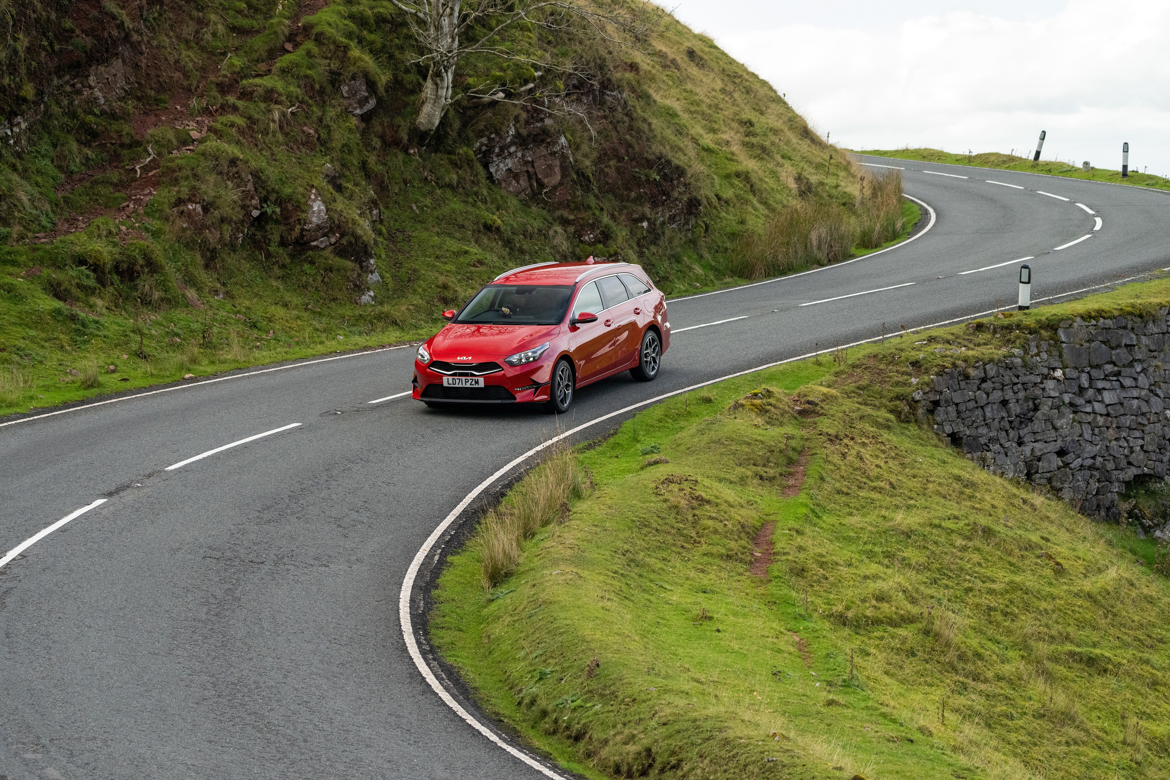Red Kia Ceed Sportswagon driving on a winding road HD Wallpaper