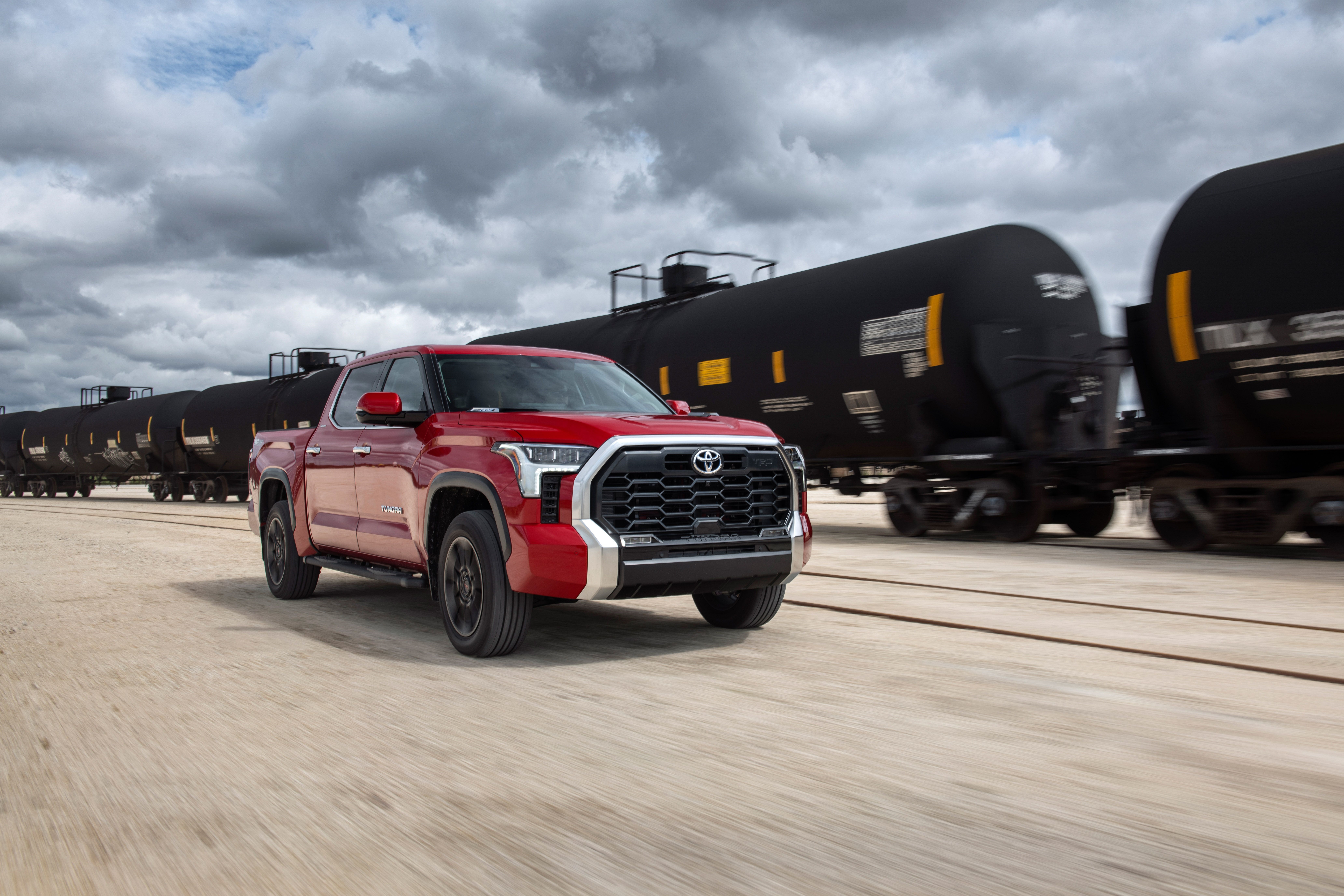 Red Toyota Tundra driving next to a train HD Wallpaper