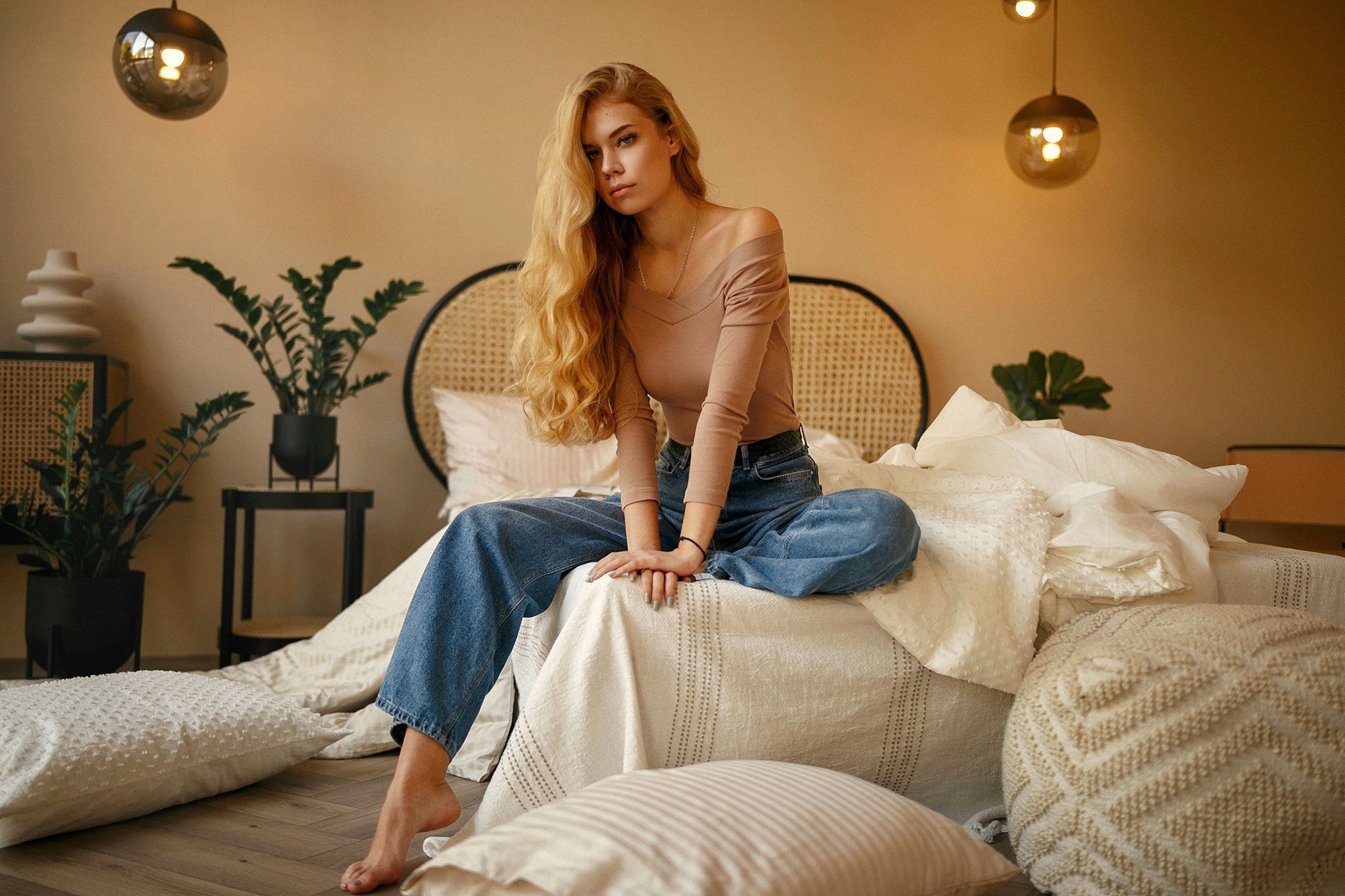 Woman in jeans and off-shoulder top sitting on a bed HD Wallpaper