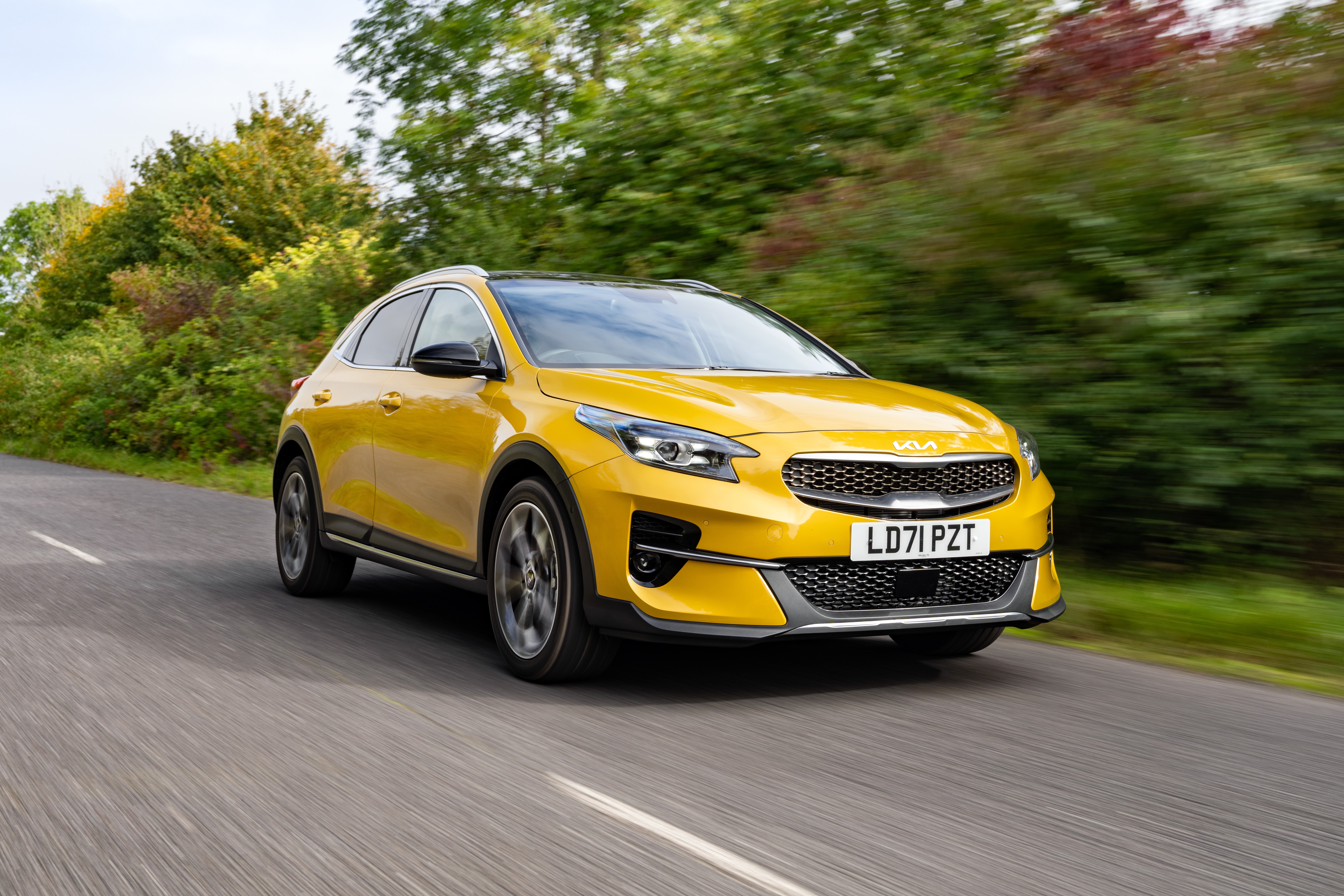 Yellow Kia XCeed driving on a road HD Wallpaper