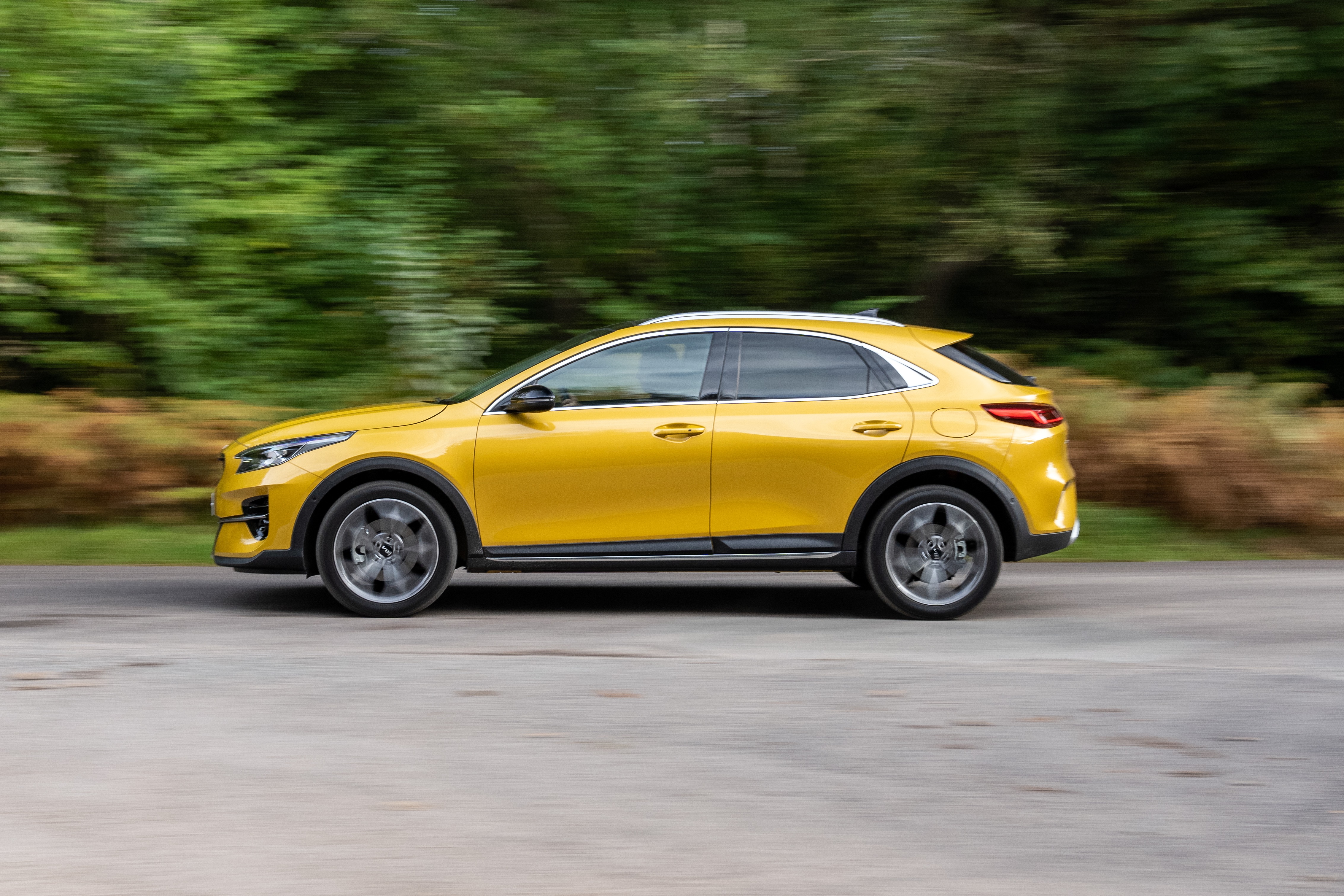 Yellow Kia XCeed driving on a road HD Wallpaper