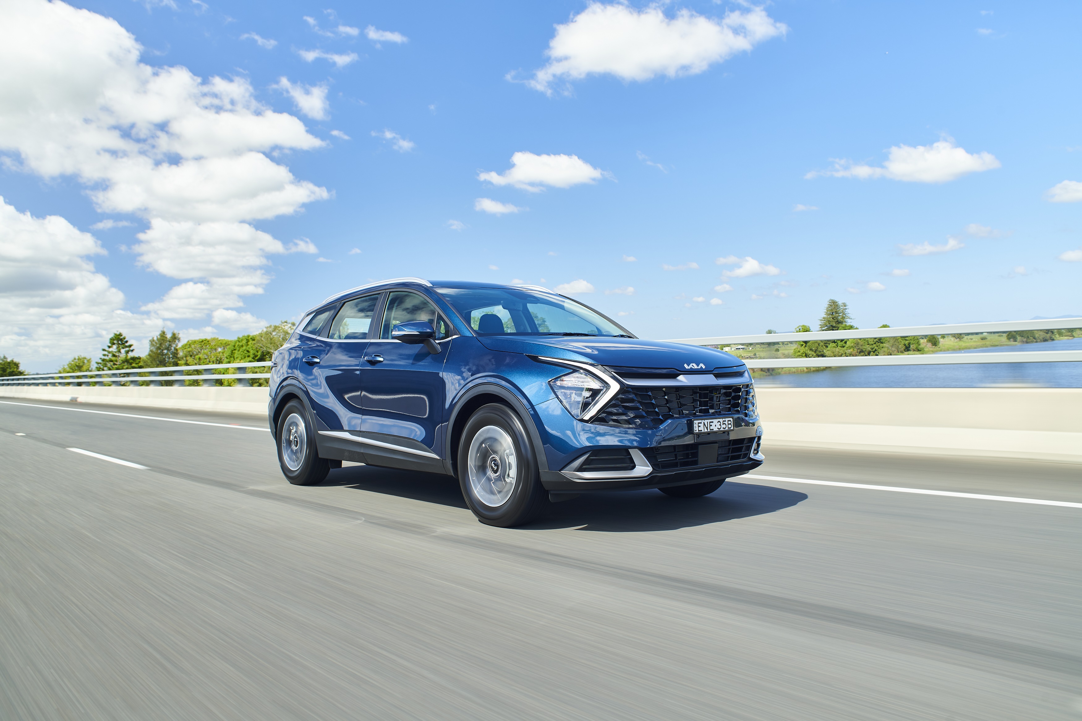 Blue Kia Sportage driving on a highway HD Wallpaper