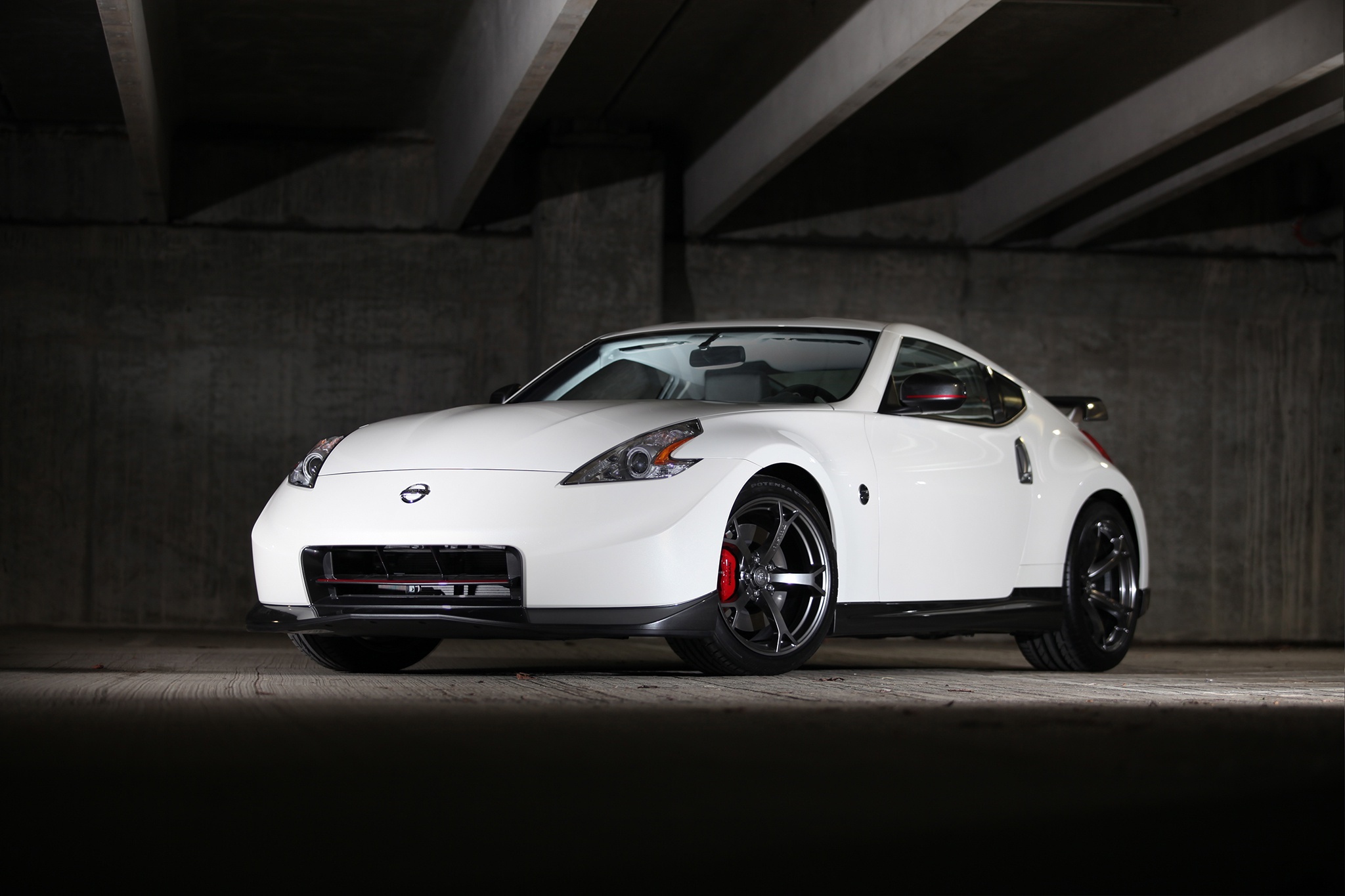 White Nissan 370Z Nismo parked under a concrete structure HD Wallpaper
