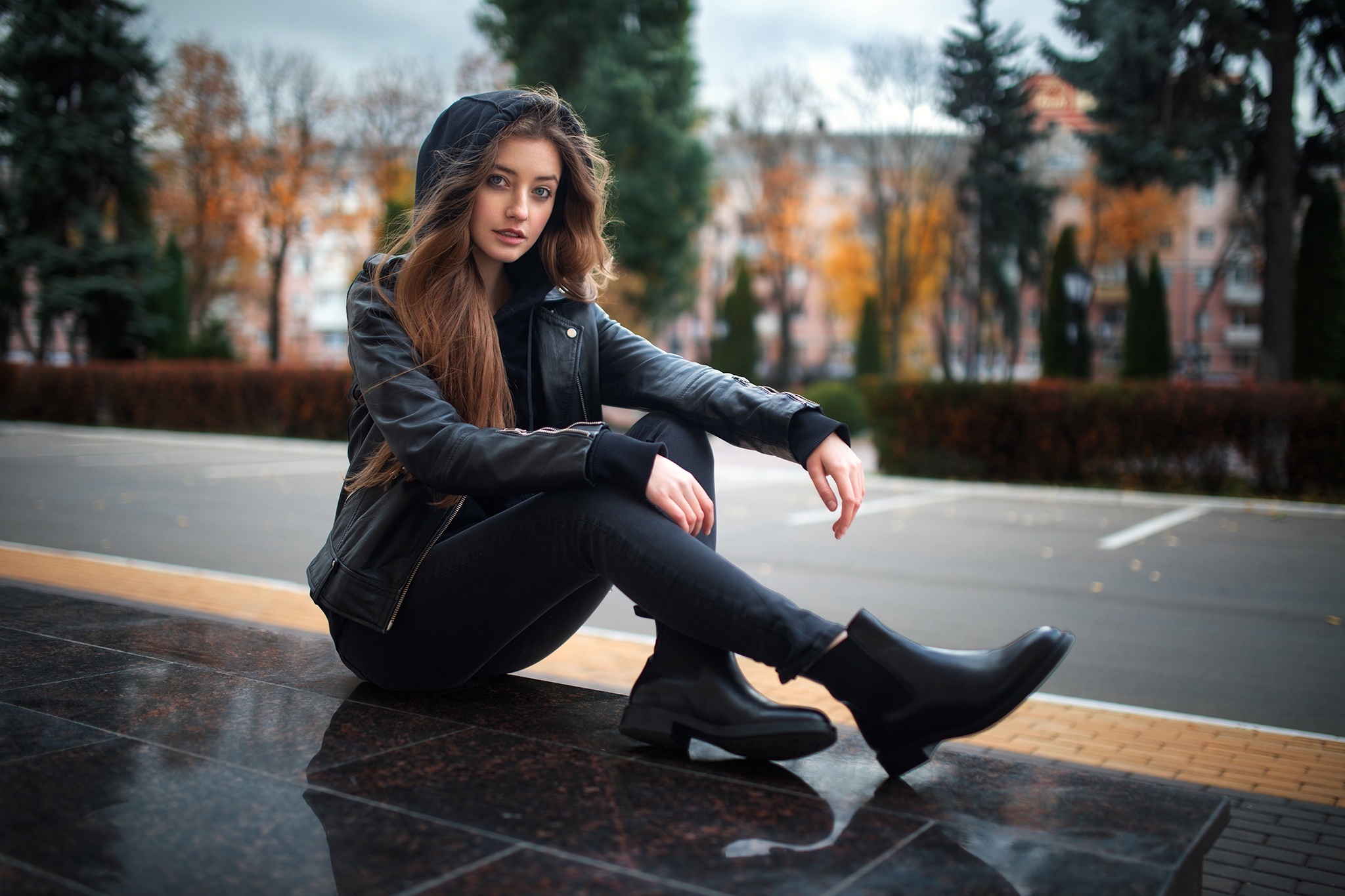 Woman in leather jacket sitting outdoors HD Wallpaper