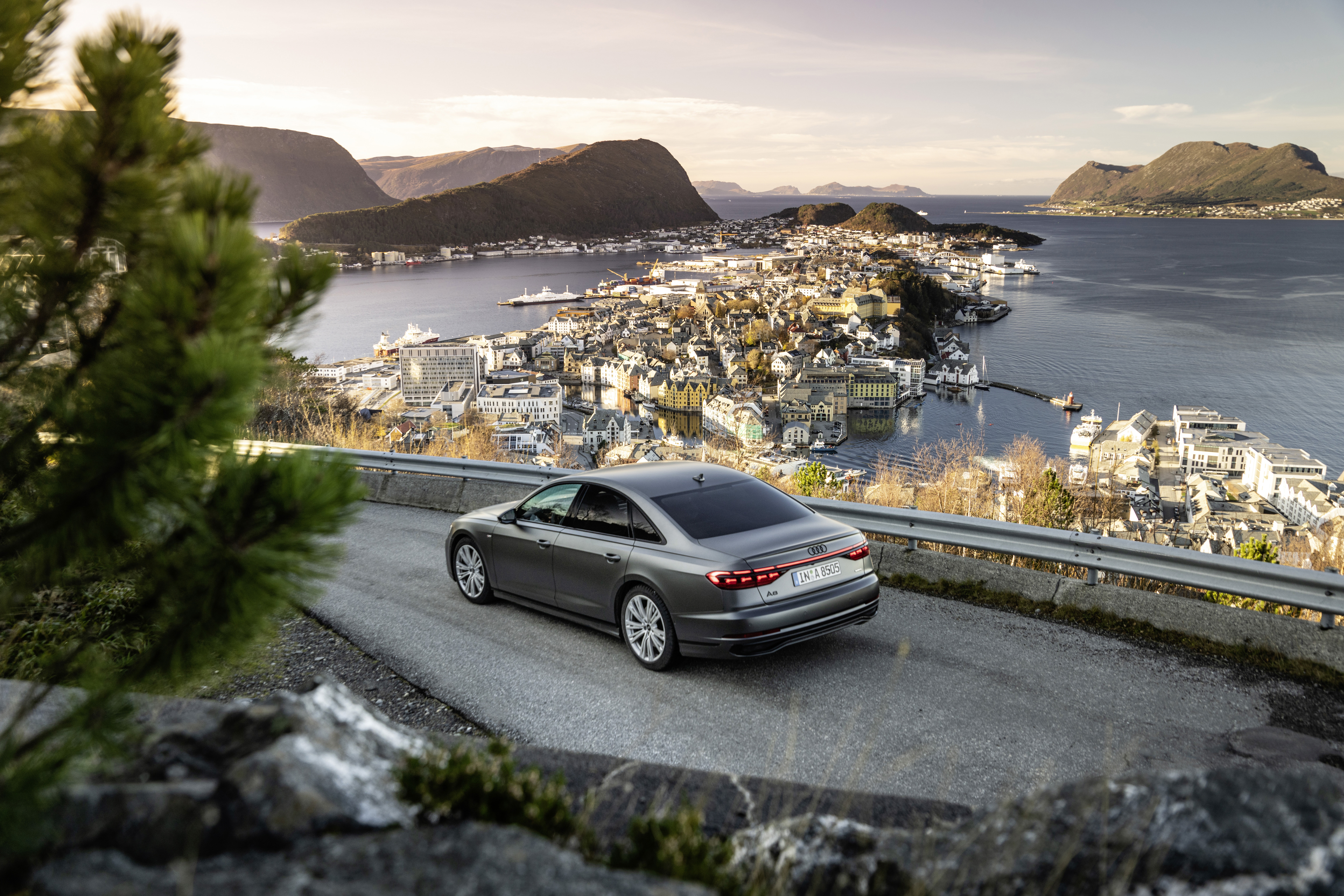 Audi A8 sedan on a scenic road overlooking a coastal town HD Wallpaper