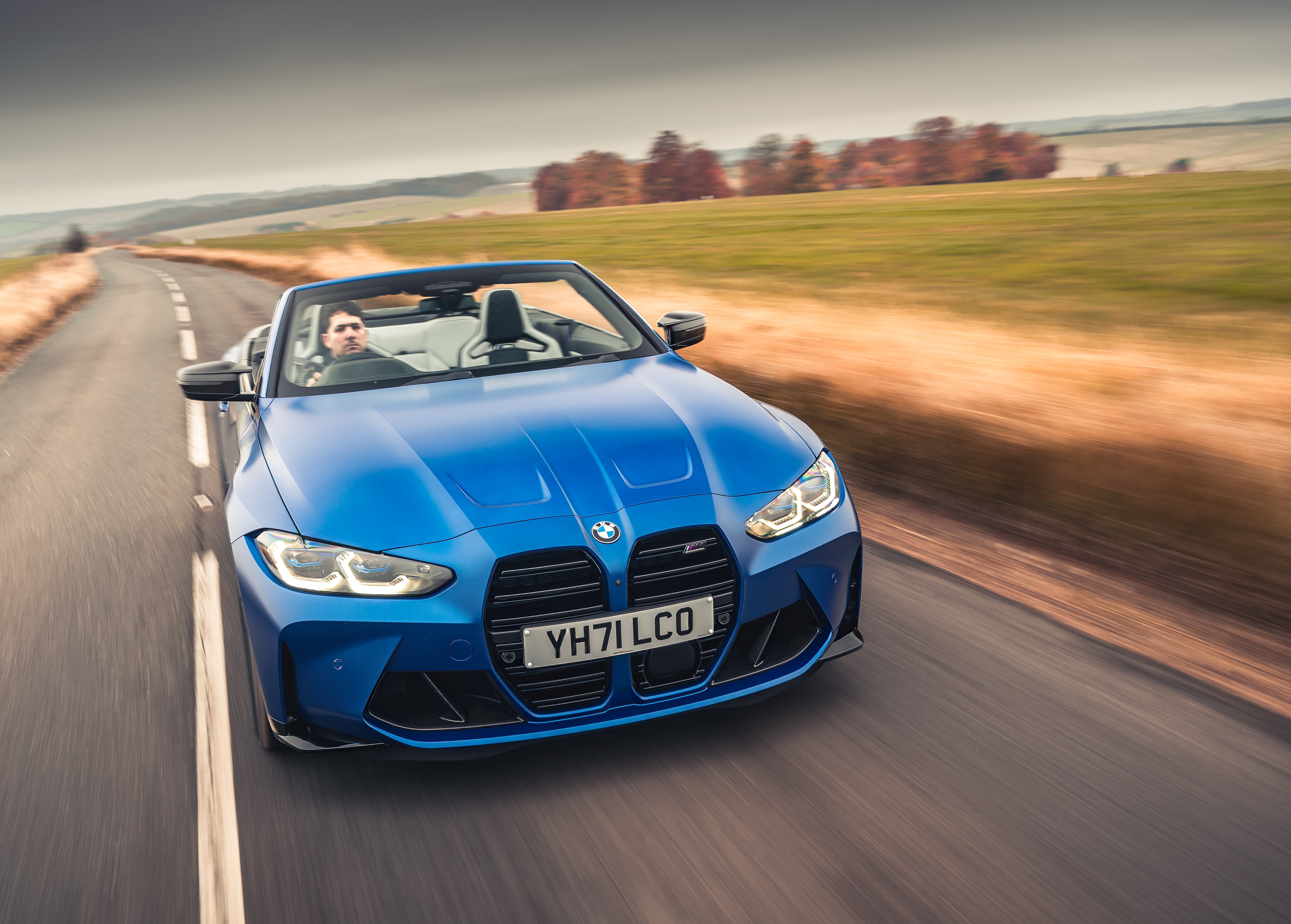Blue BMW M4 Competition Convertible driving on a road HD Wallpaper