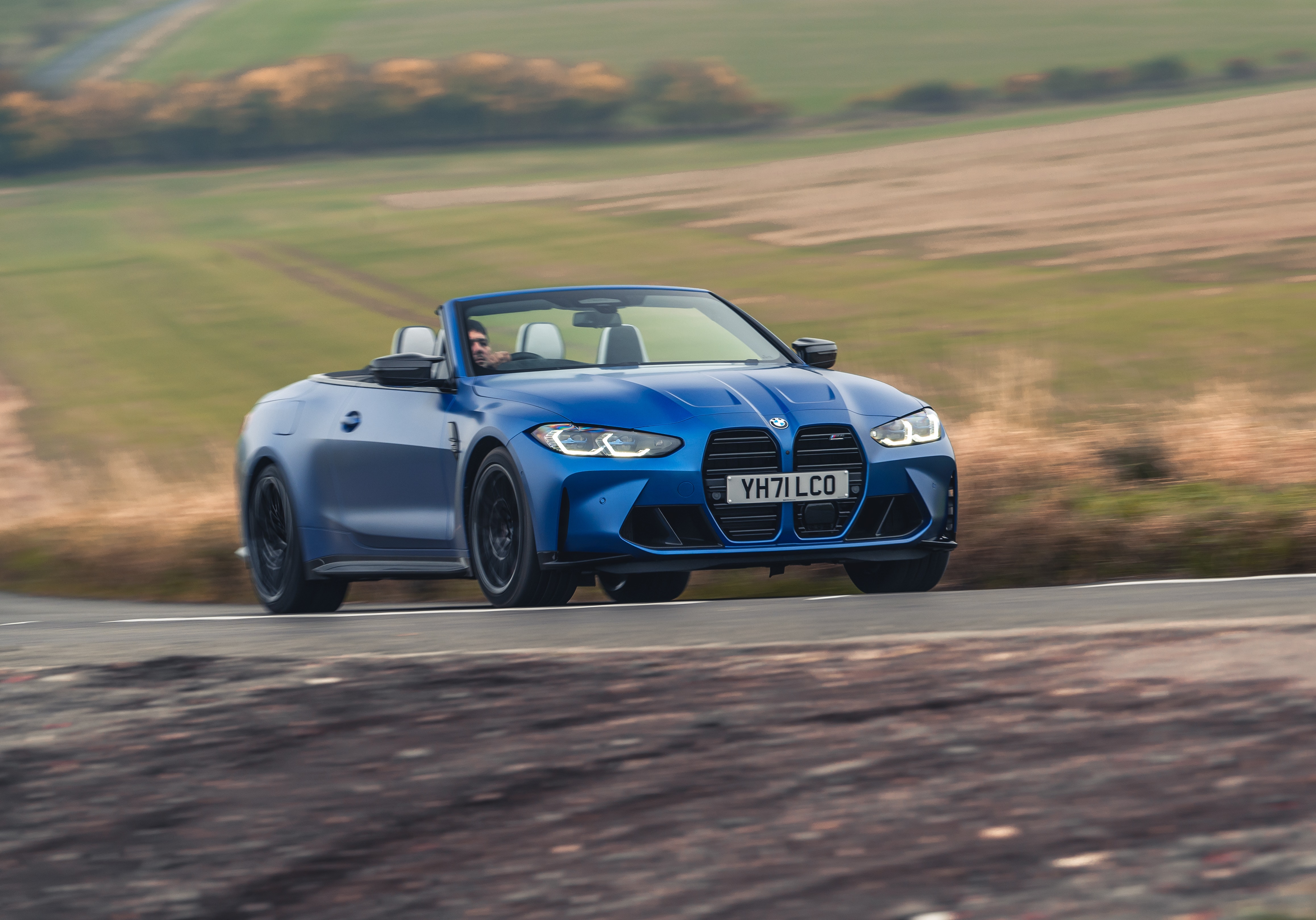 Blue BMW M4 Competition Convertible driving on a road HD Wallpaper