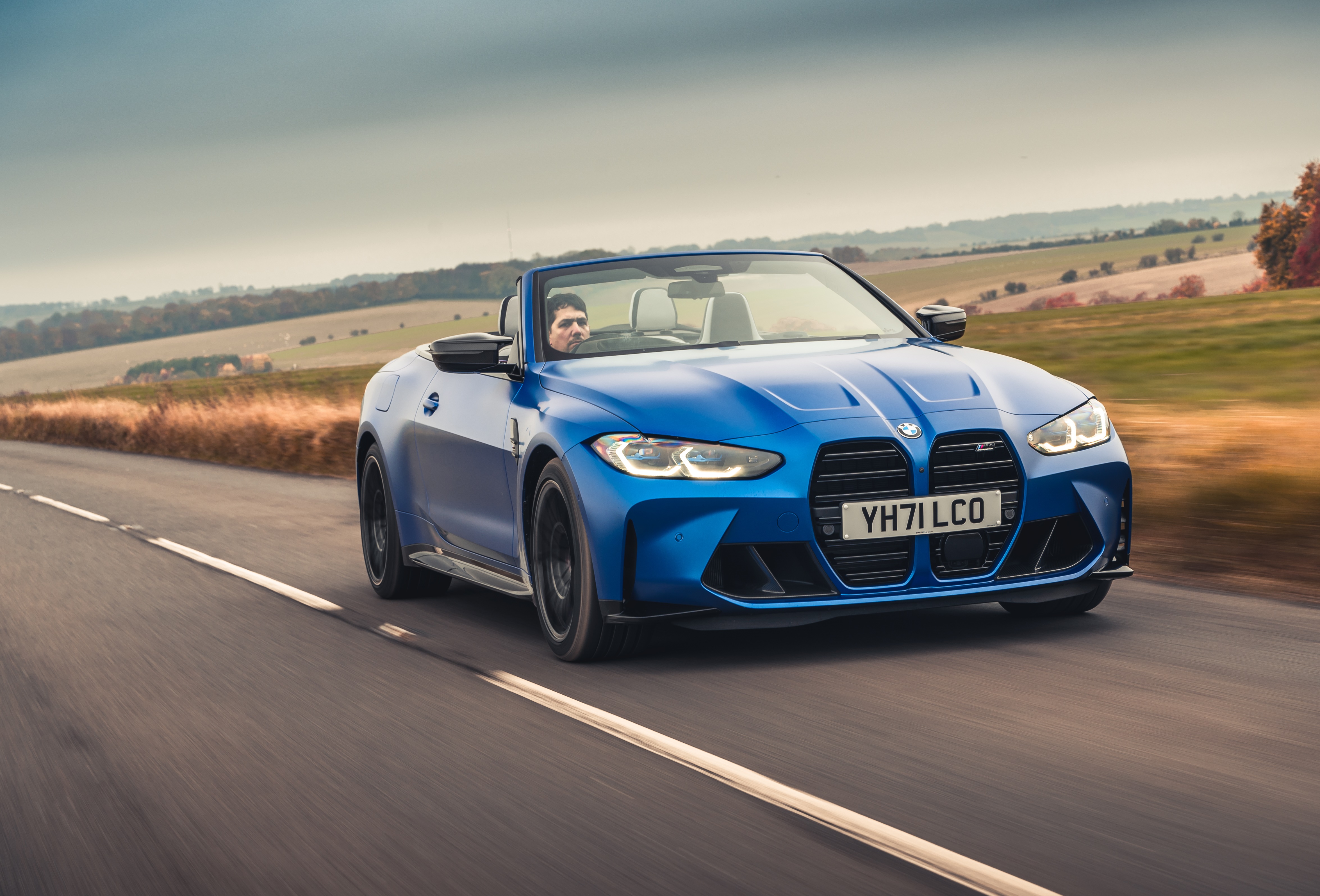 Blue BMW M4 Competition Convertible driving on a road HD Wallpaper