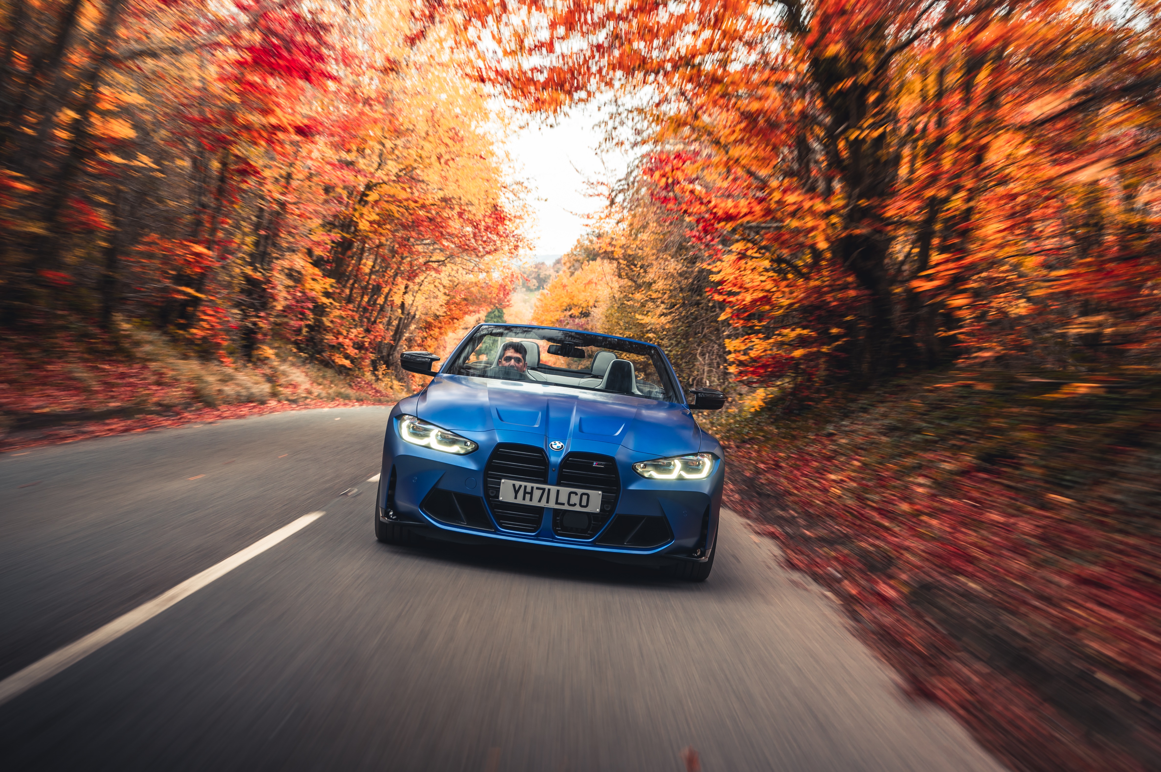 Blue BMW M4 Competition Convertible driving on autumn road HD Wallpaper