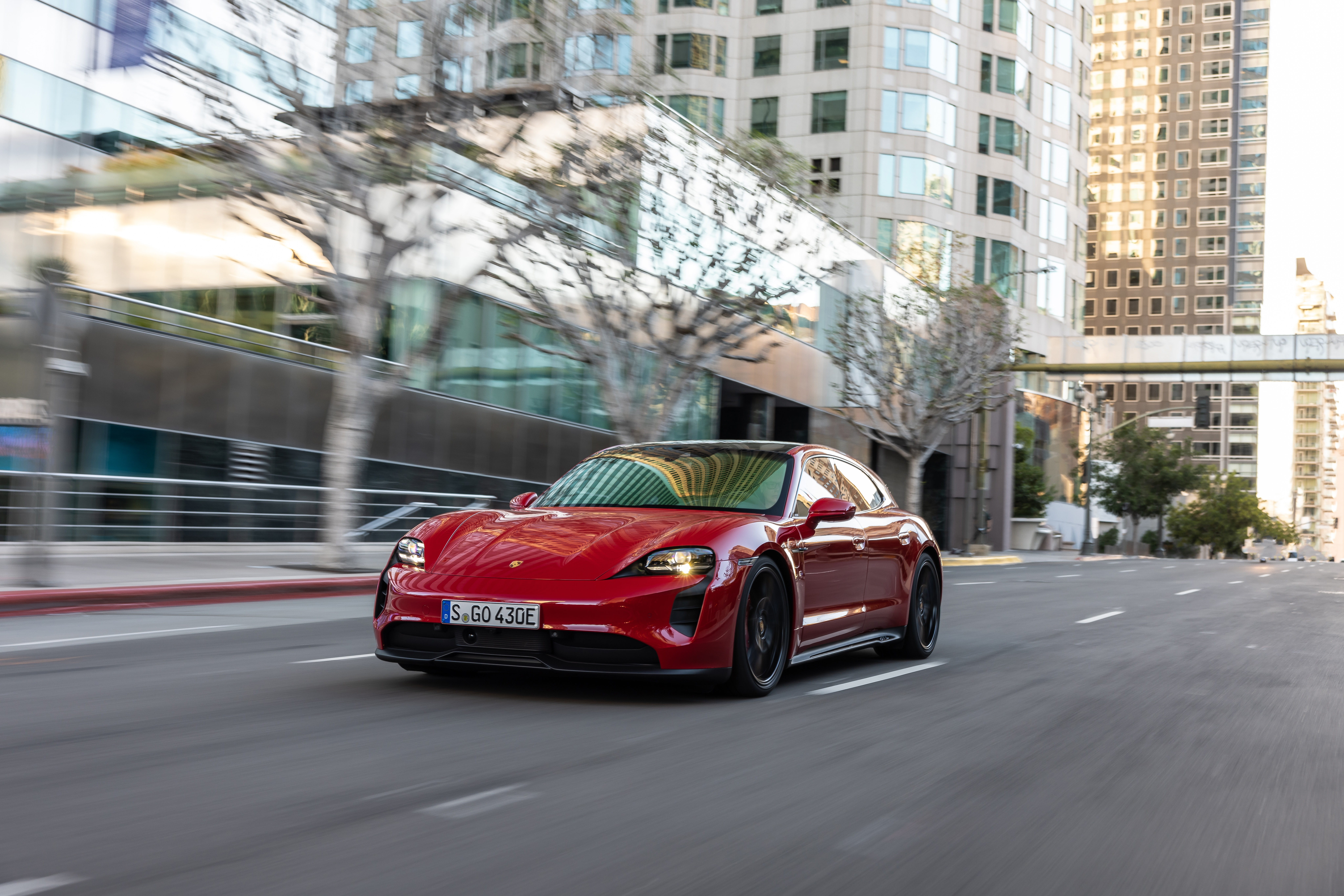 Red Porsche Taycan GTS Sport Turismo driving on city street HD Wallpaper