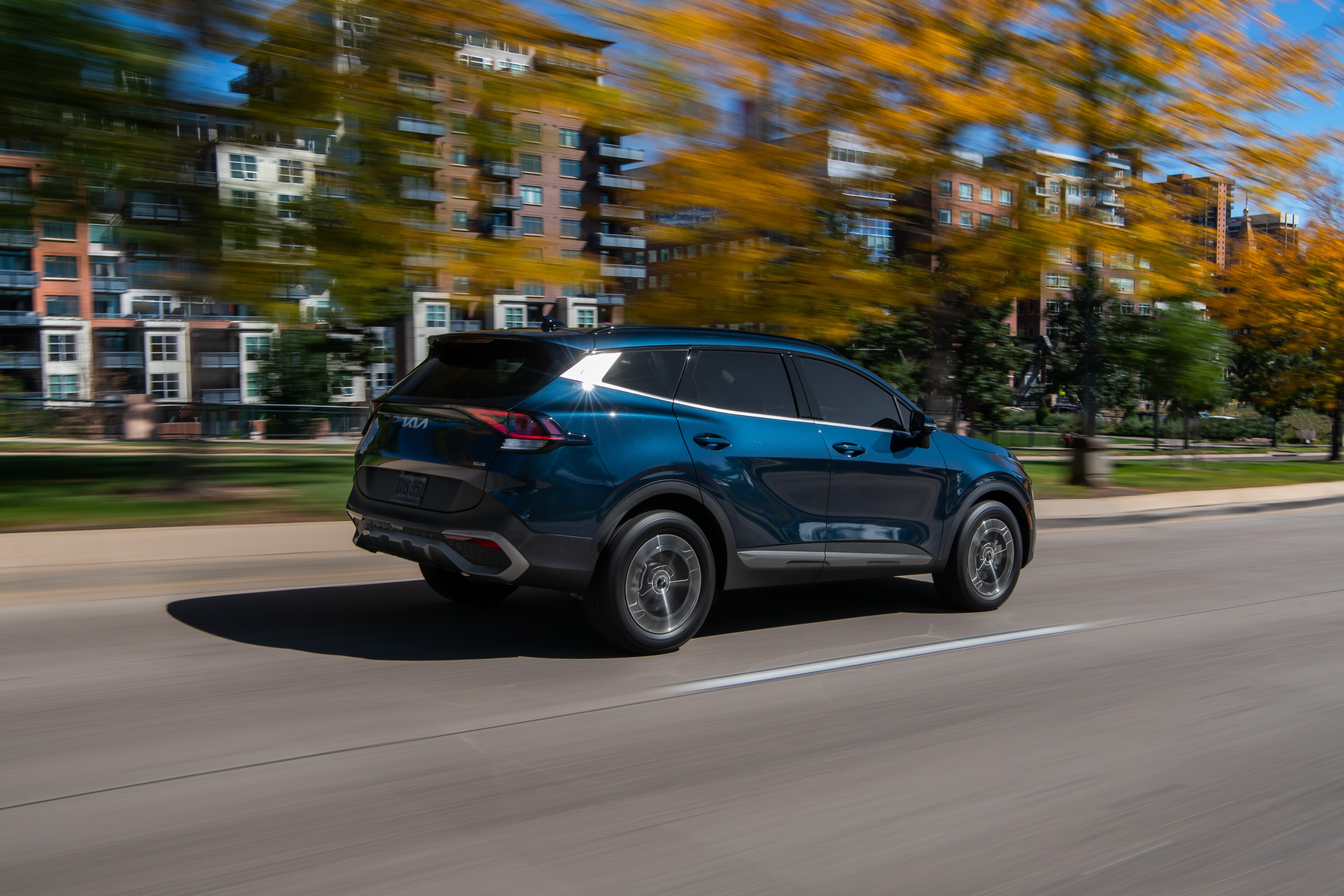 Blue Kia Sportage HEV driving on a road HD Wallpaper