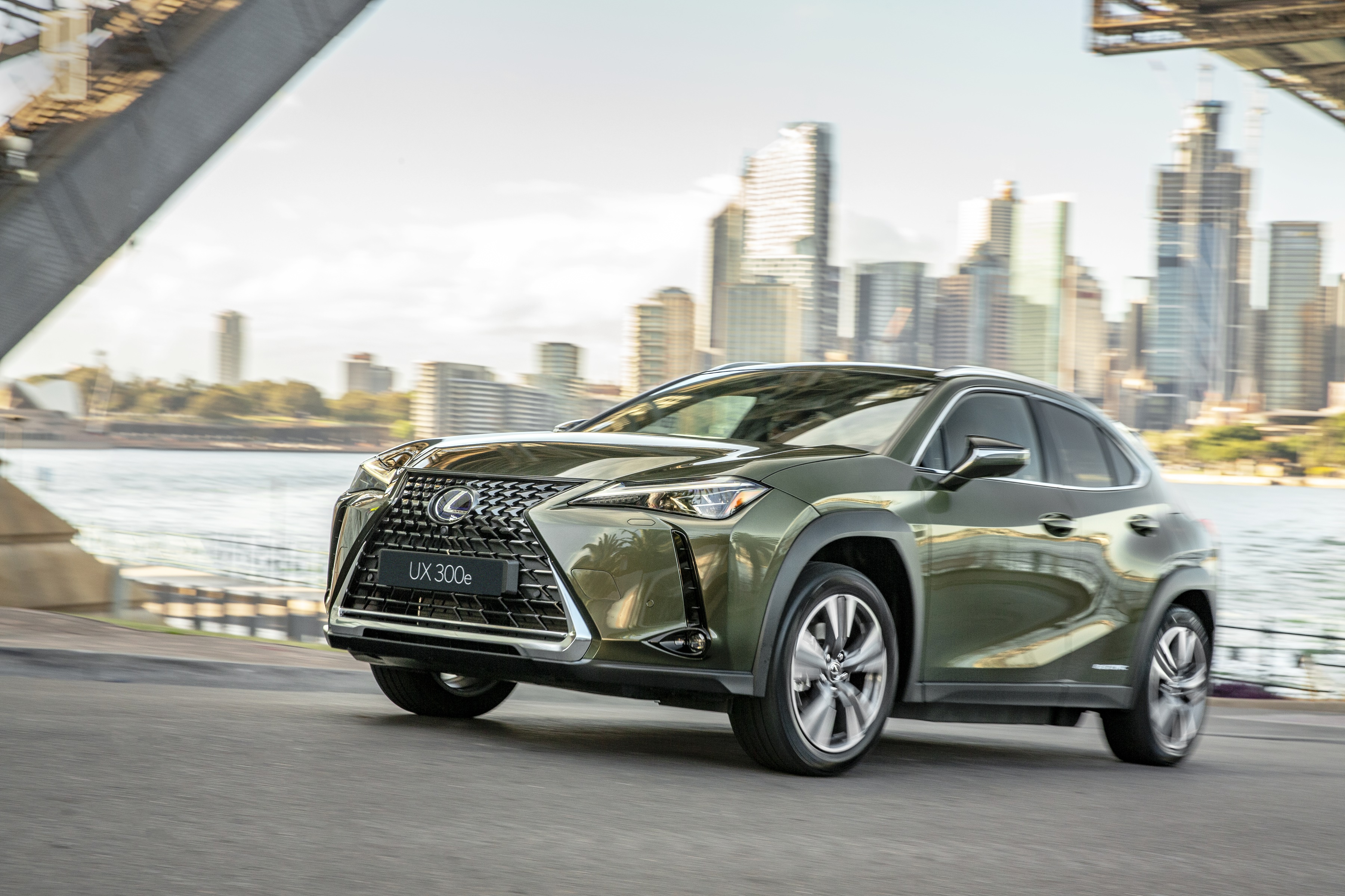 Lexus UX 300e SUV driving near city skyline HD Wallpaper
