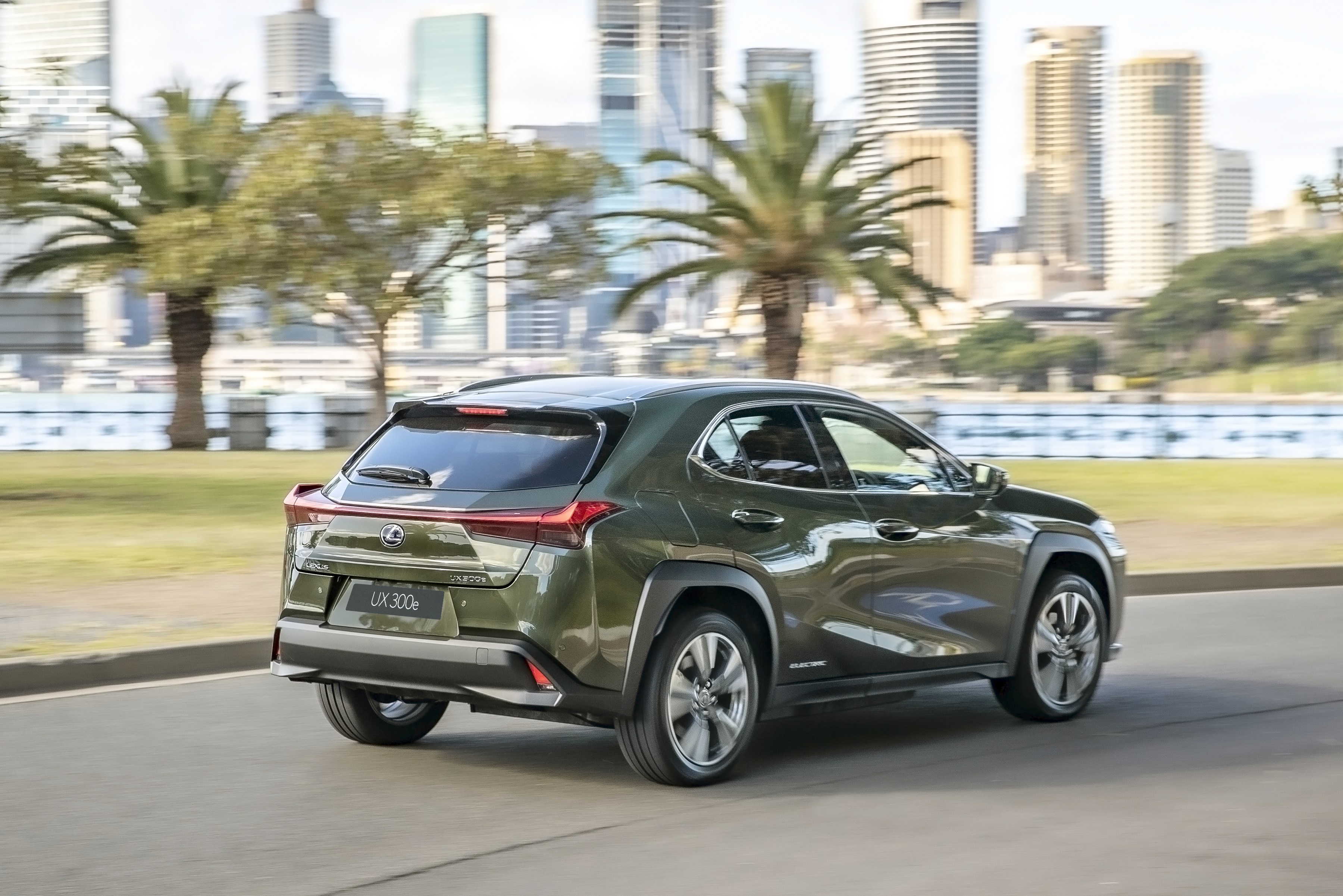 Green Lexus UX 300e driving in city HD Wallpaper