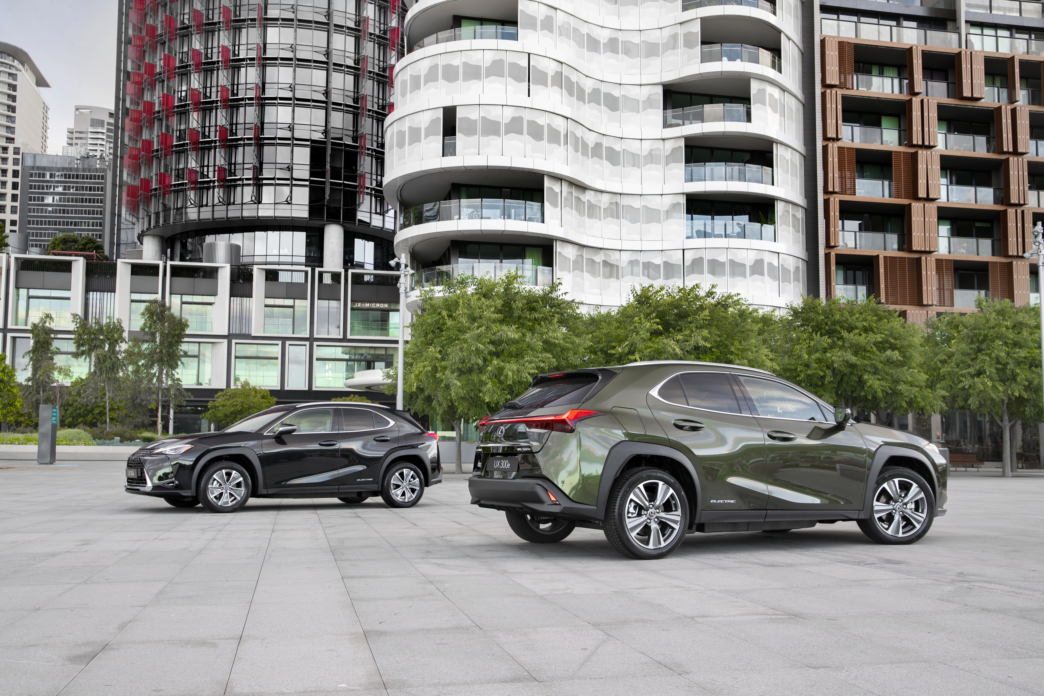 Two Lexus UX 300e SUVs parked in an urban setting HD Wallpaper