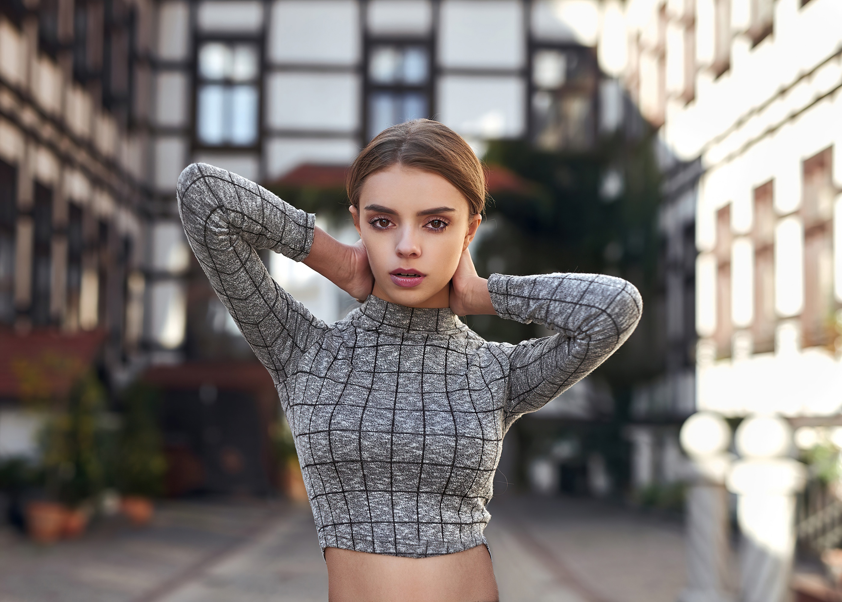 Woman with hands behind head in front of buildings HD Wallpaper