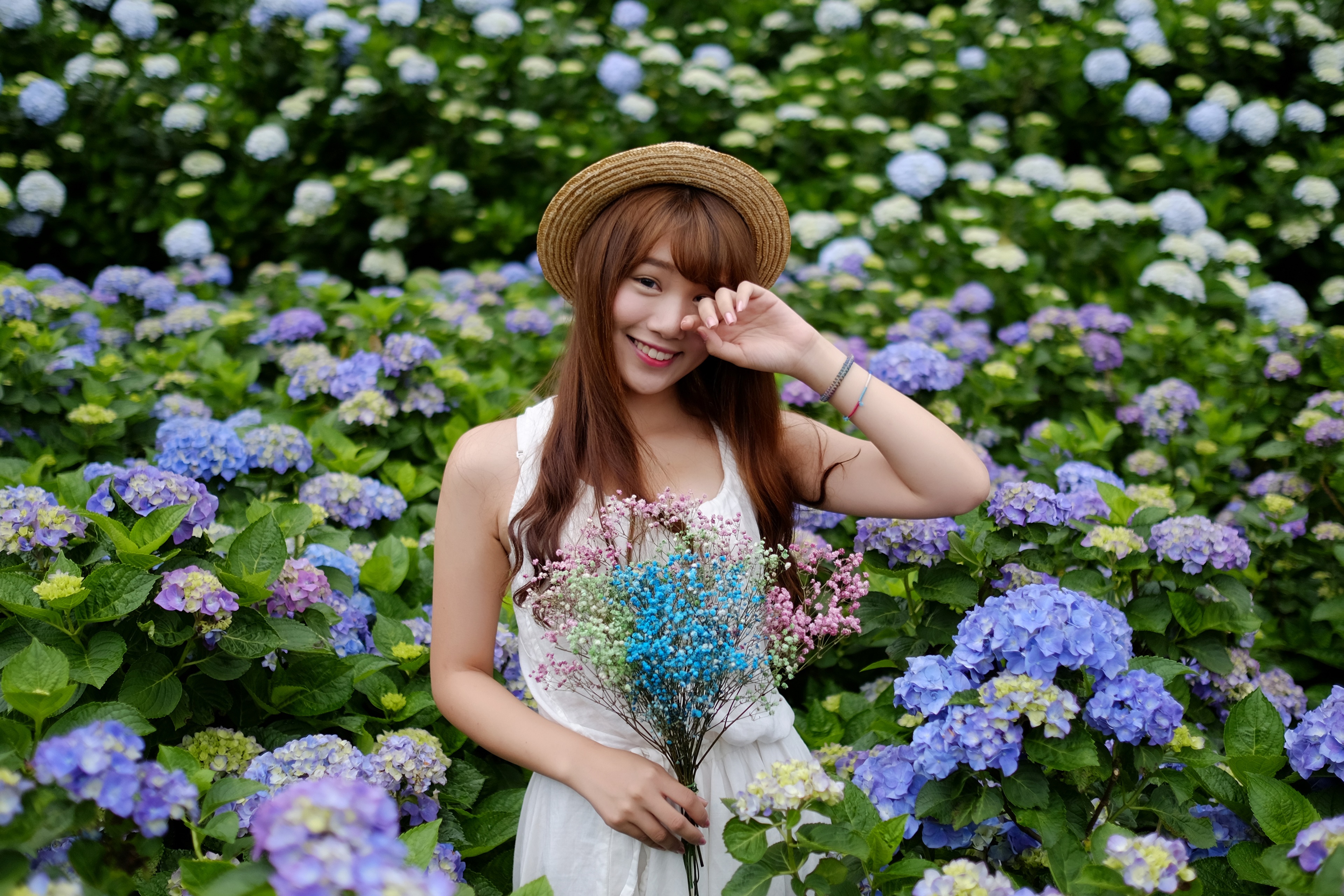 Asian woman in straw hat holding flowers in hydrangea garden HD Wallpaper
