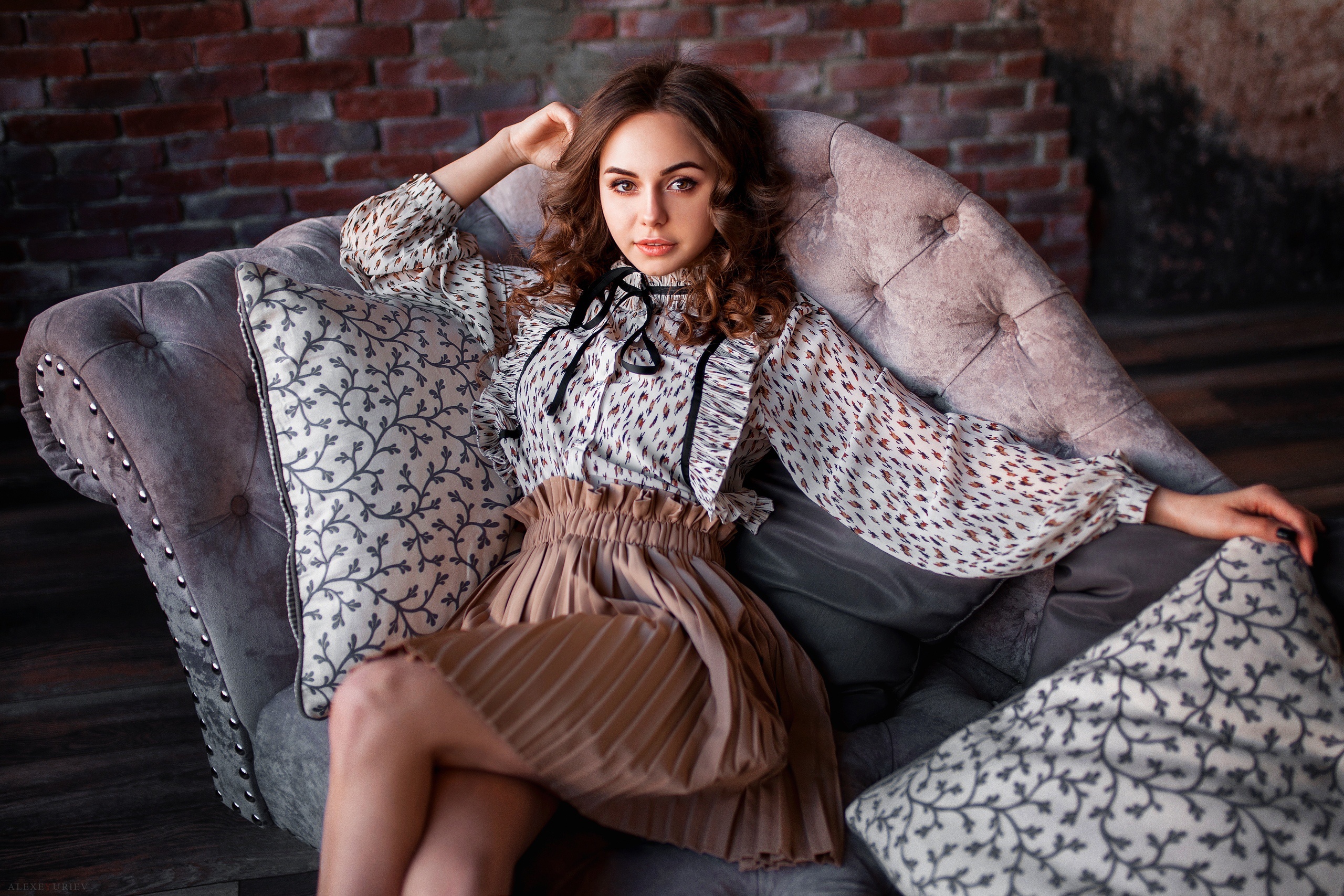 Brunette woman sitting on a sofa HD Wallpaper