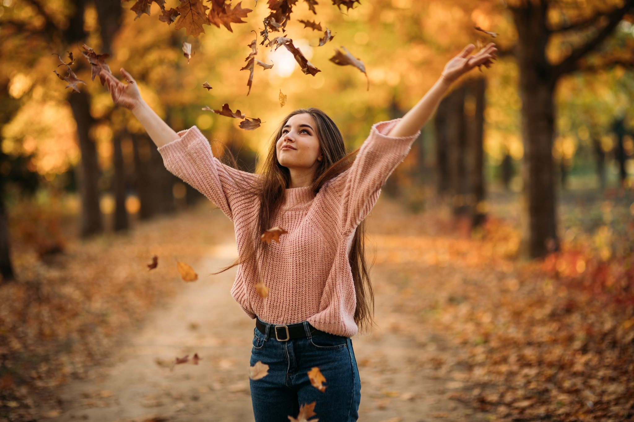 Young woman in a pink sweater throwing leaves in autumn park HD Wallpaper