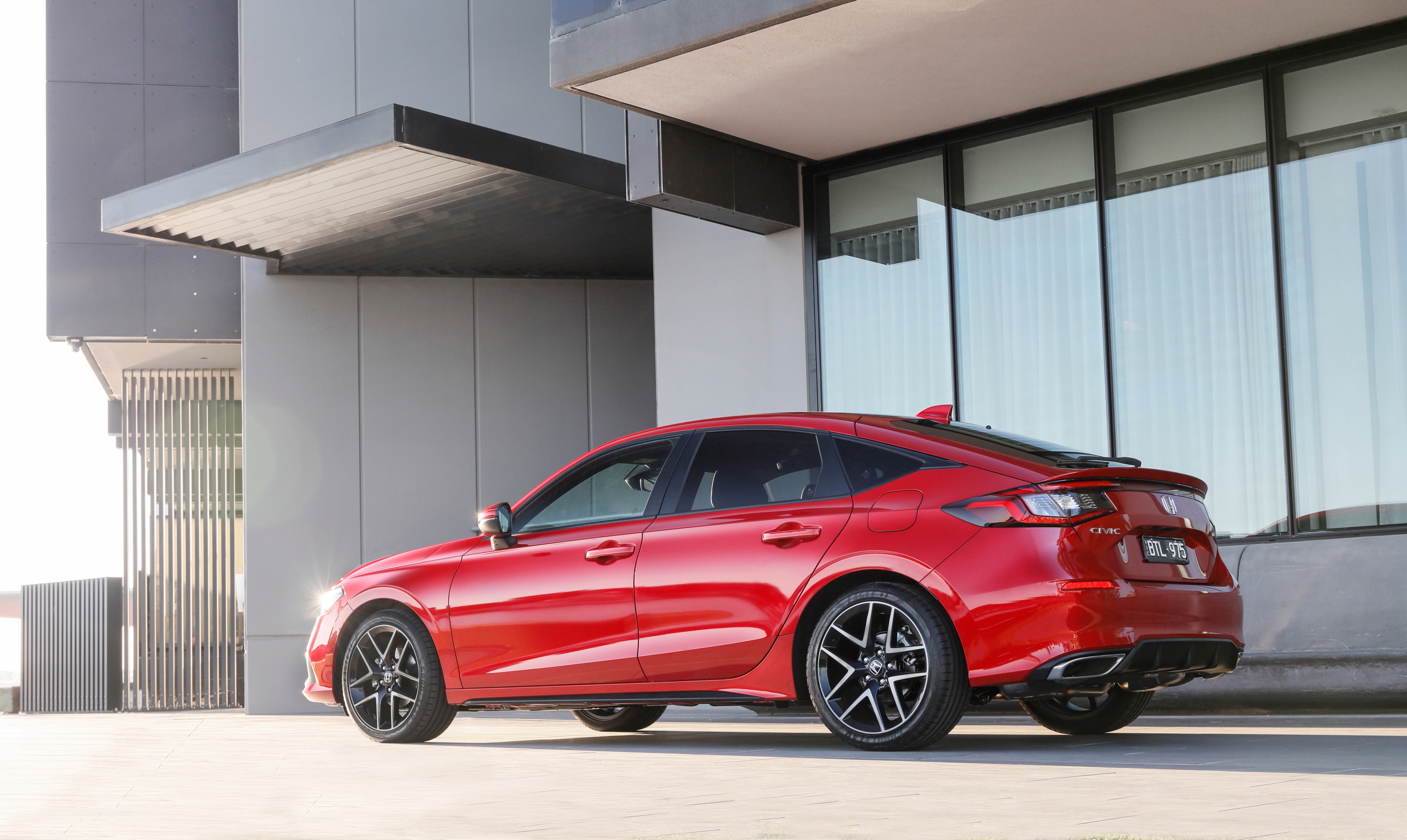 Red Honda Civic Hatchback parked near a modern building HD Wallpaper