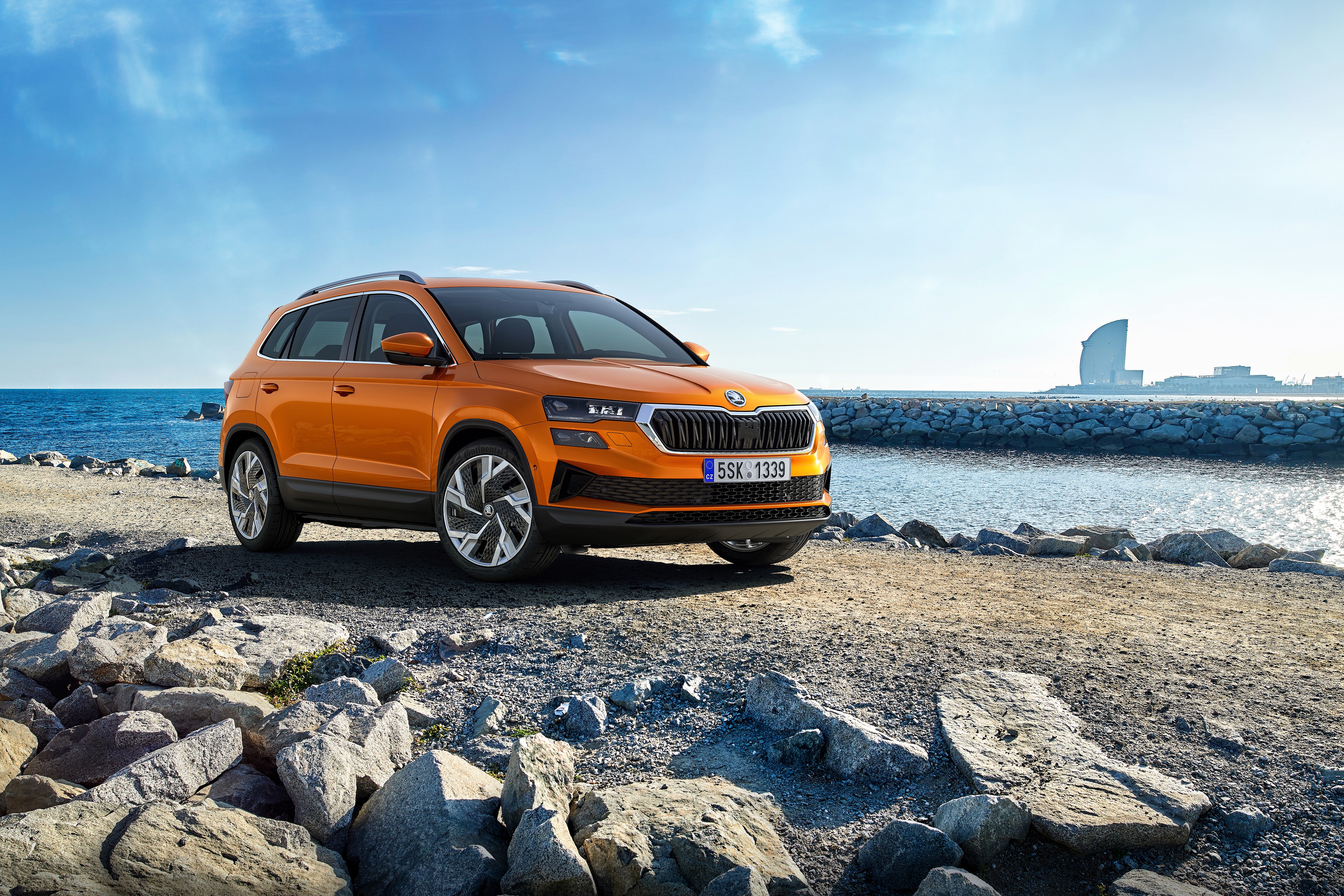 Orange Škoda Karoq SUV parked by the sea HD Wallpaper