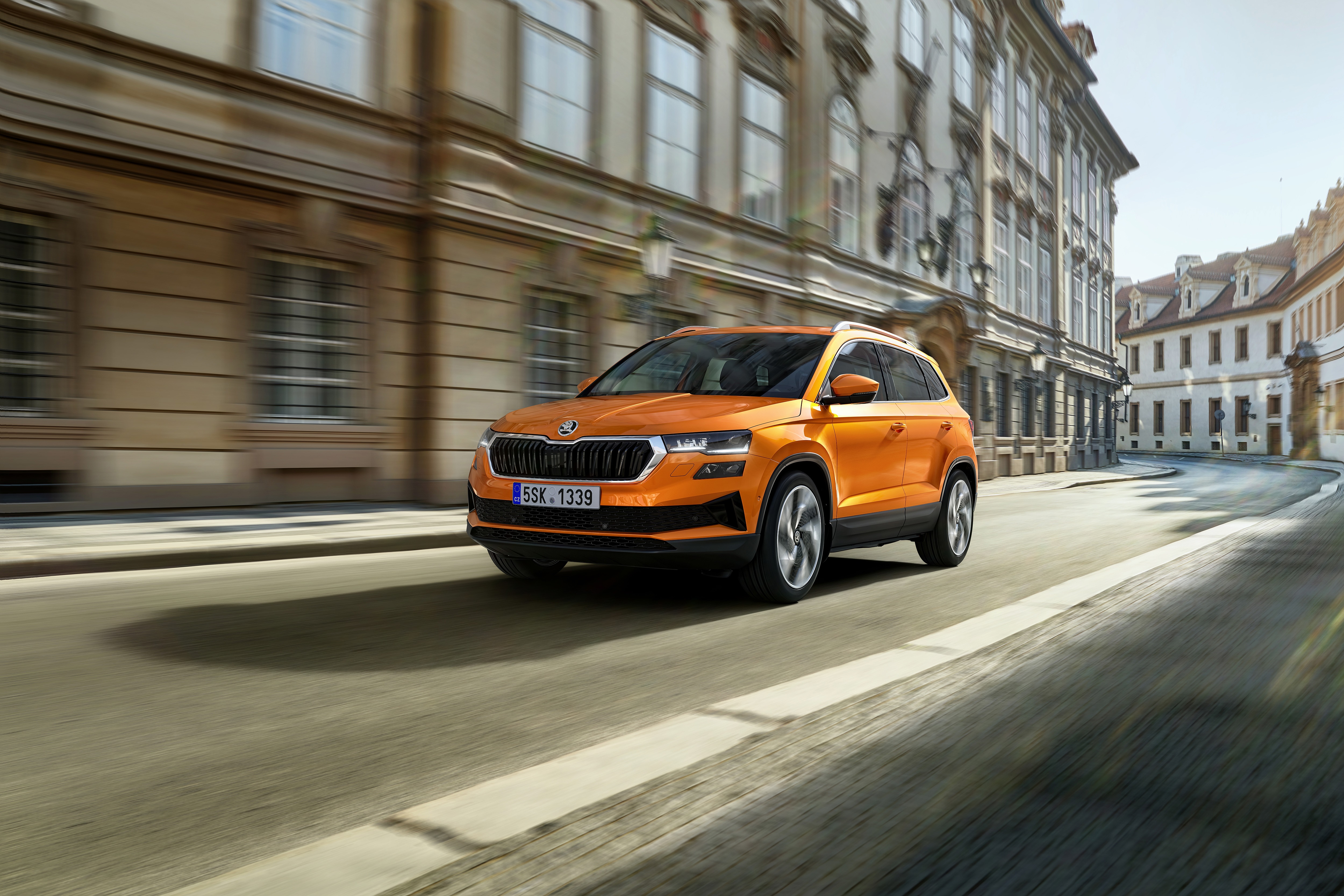 Orange Škoda Karoq SUV driving on a street HD Wallpaper
