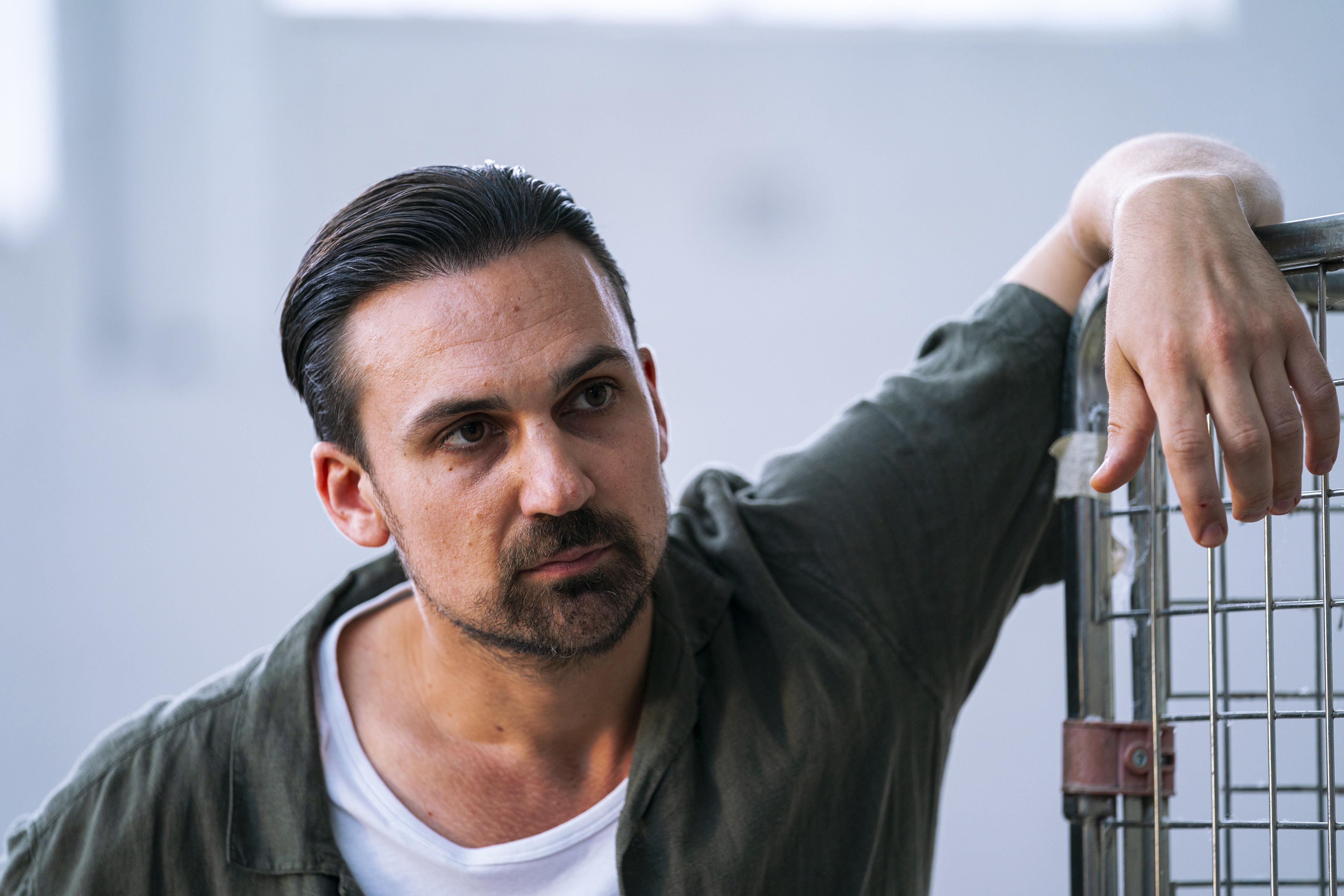 Henry Lloyd-Hughes leaning on a metal rack HD Wallpaper