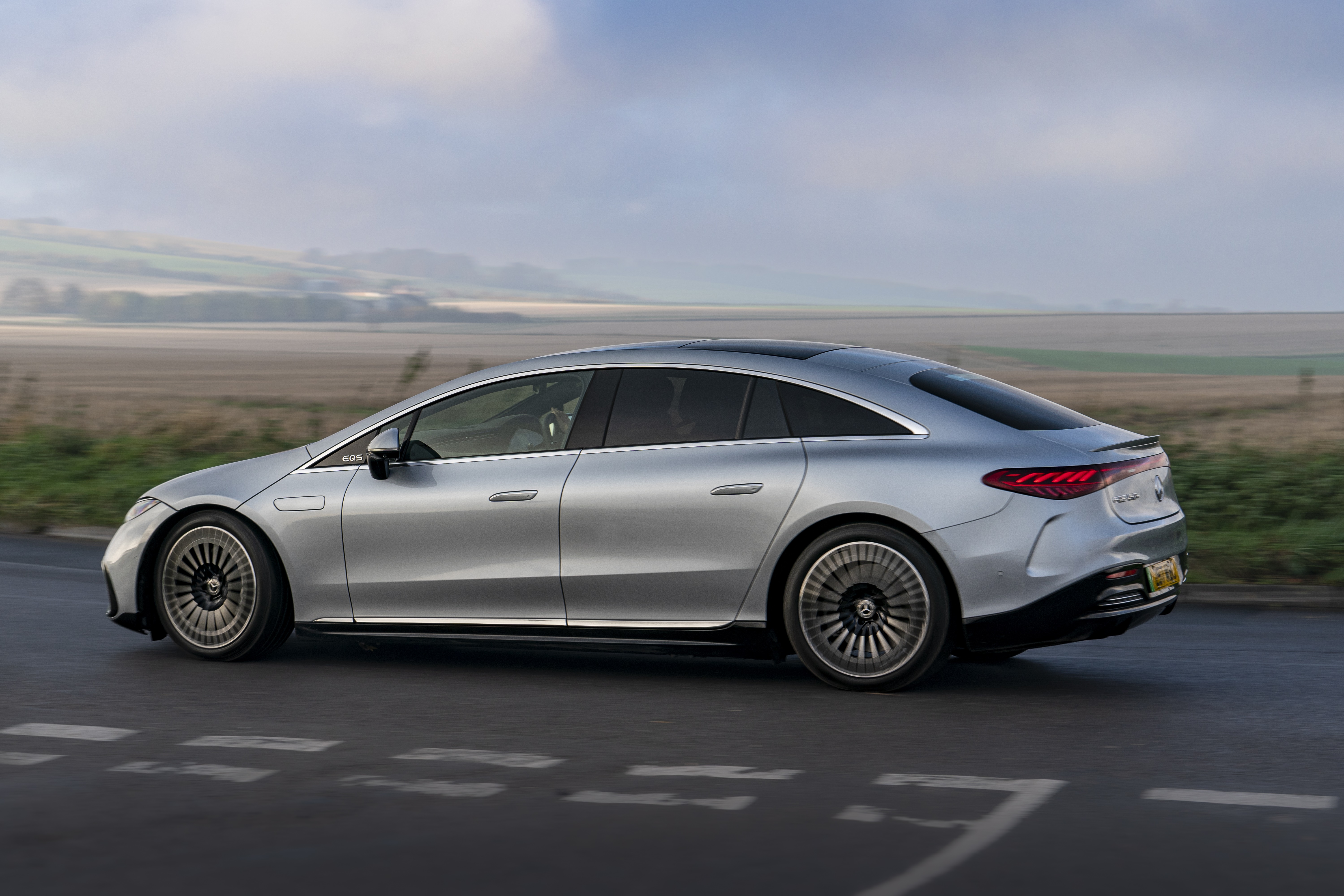Silver Mercedes-Benz EQS 450 AMG Line driving on road HD Wallpaper