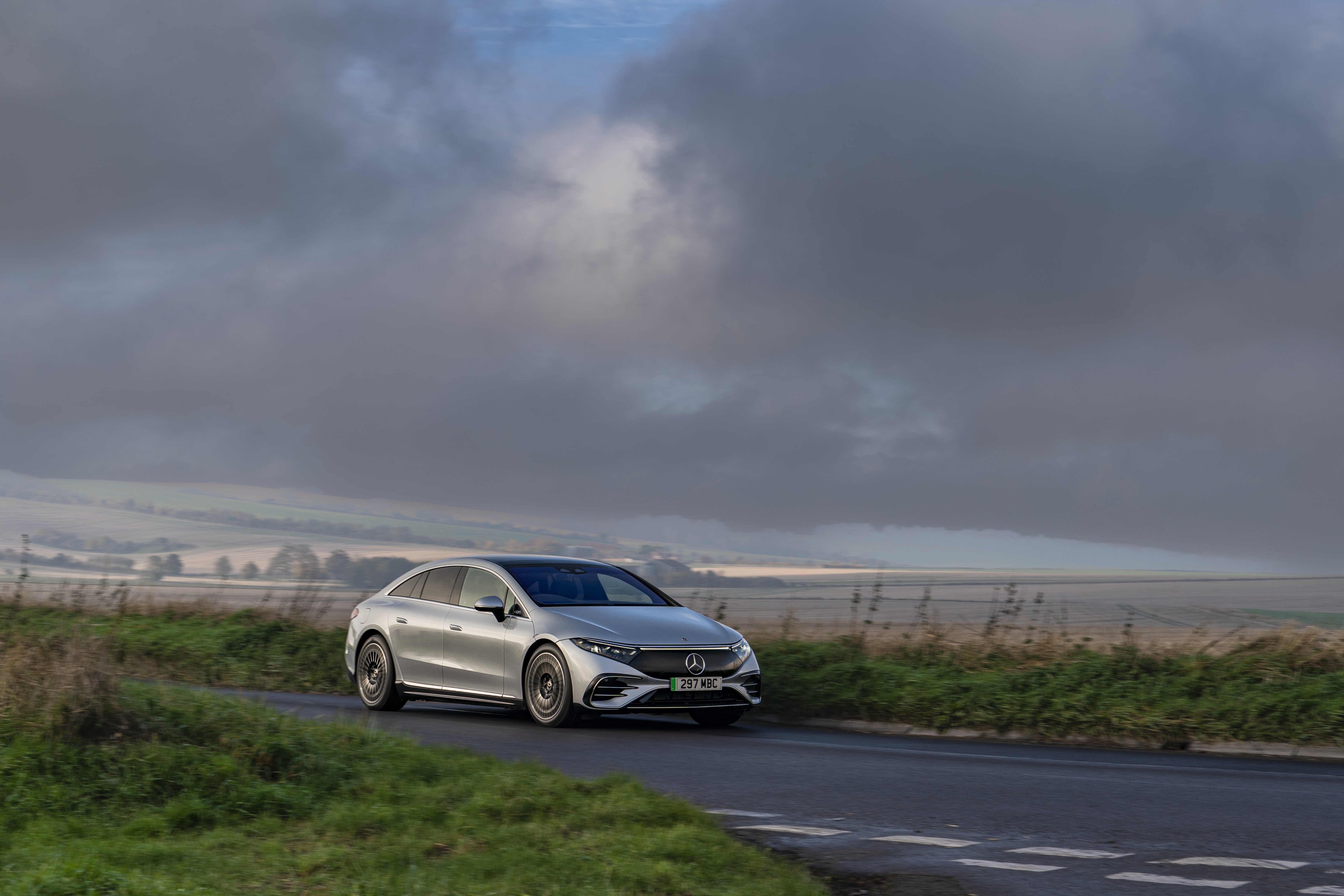 Silver Mercedes-Benz EQS driving on a road HD Wallpaper