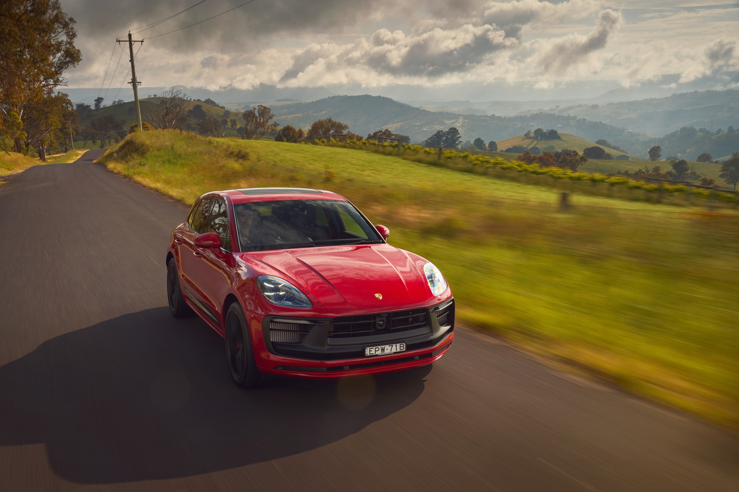 Red Porsche Macan GTS driving on a country road HD Wallpaper