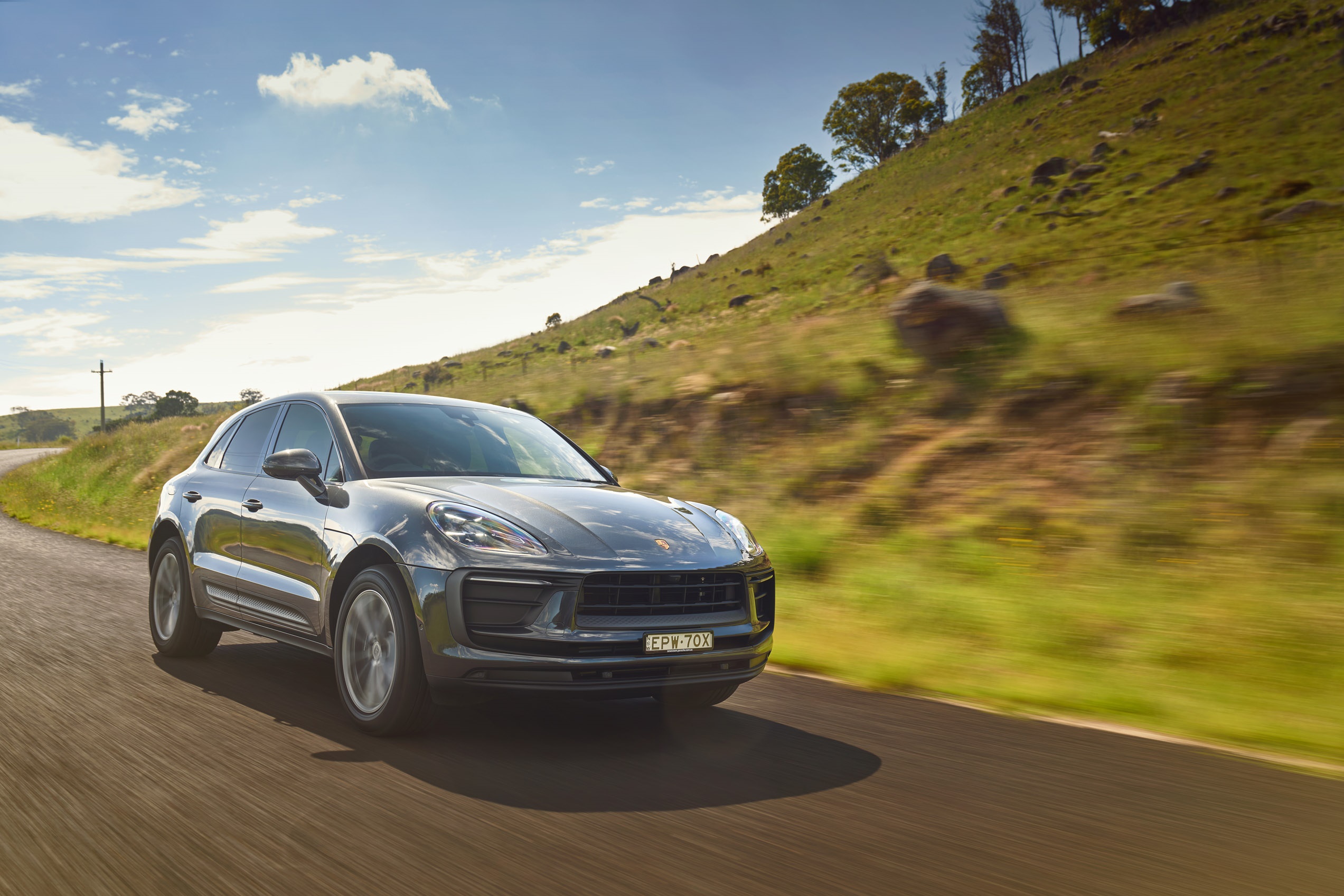 Porsche Macan driving on a rural road HD Wallpaper