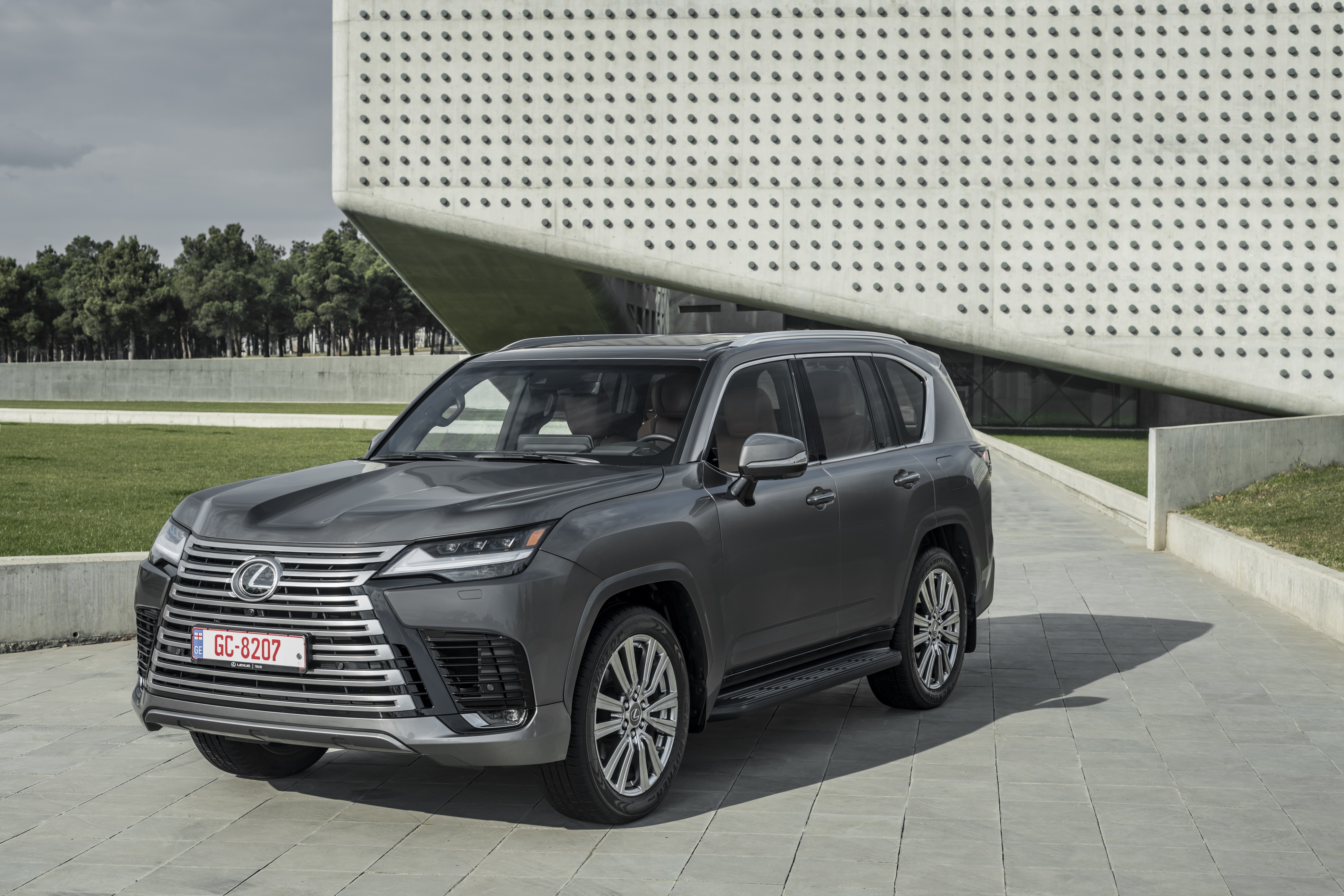 Lexus LX 600 SUV parked in front of a modern building HD Wallpaper