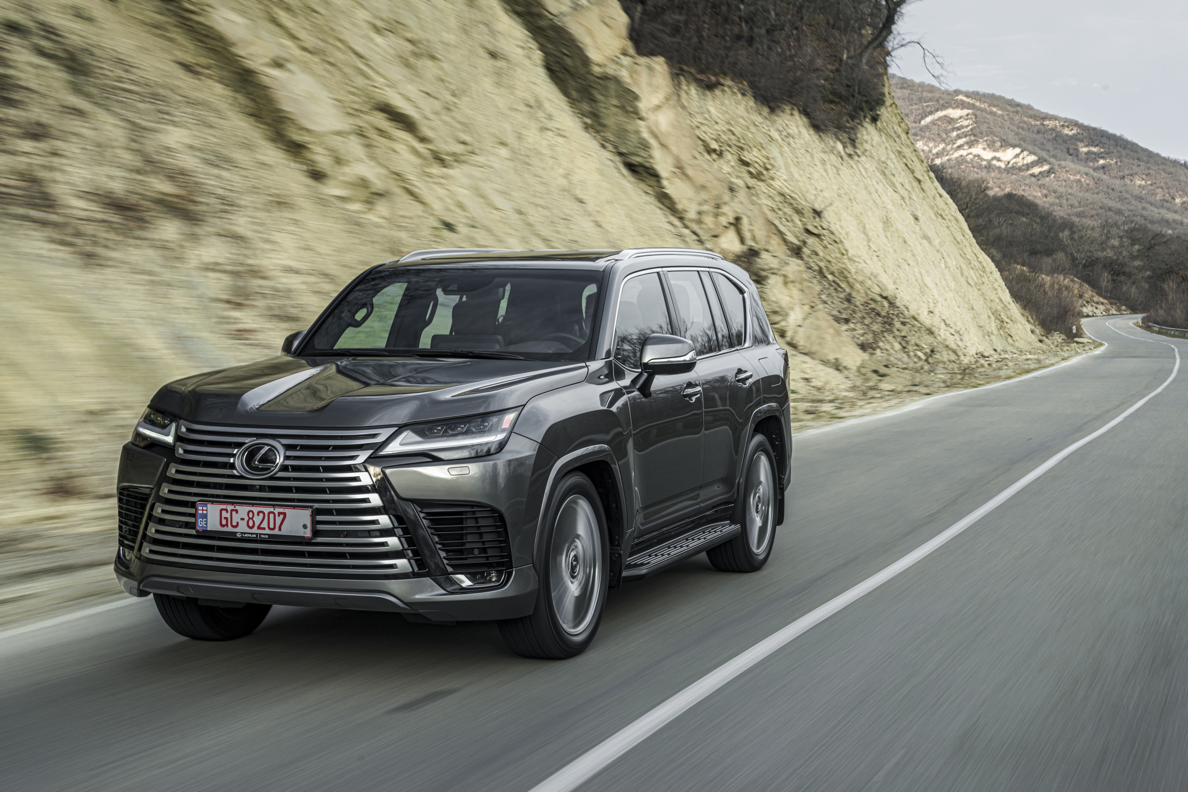 Lexus LX 600 SUV driving on a winding road HD Wallpaper