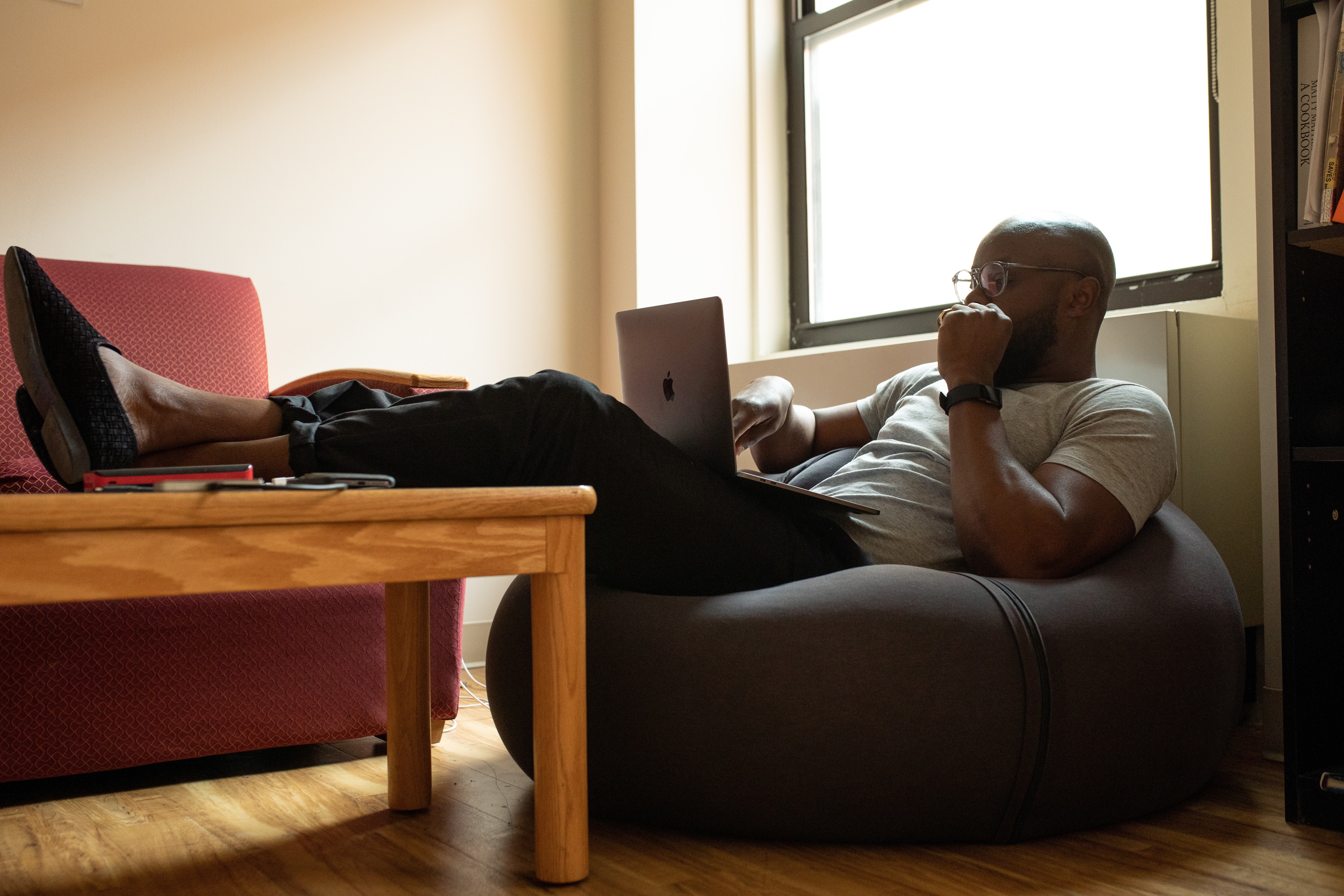 Man working on Macbook on beanbag chair HD Wallpaper