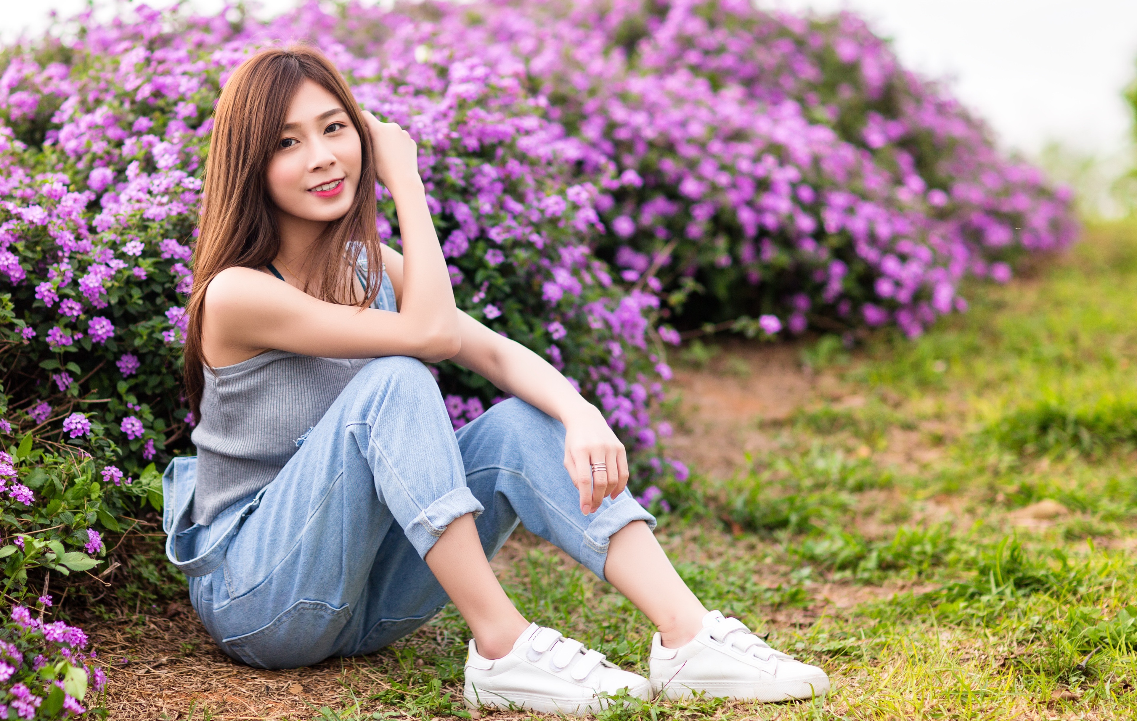 Asian woman with brunette hair sitting in flowers HD Wallpaper