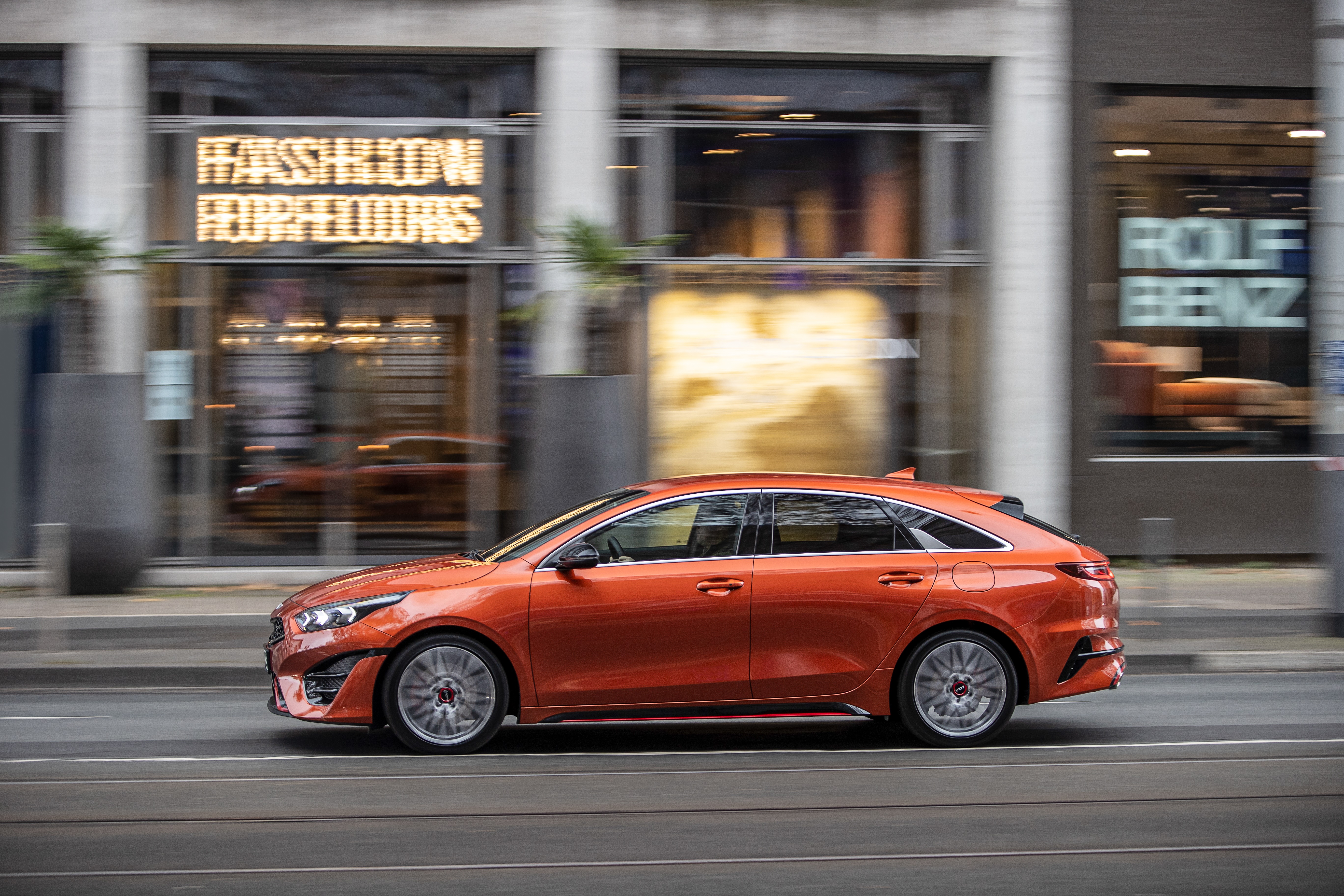 Orange Kia ProCeed GT driving on city street HD Wallpaper