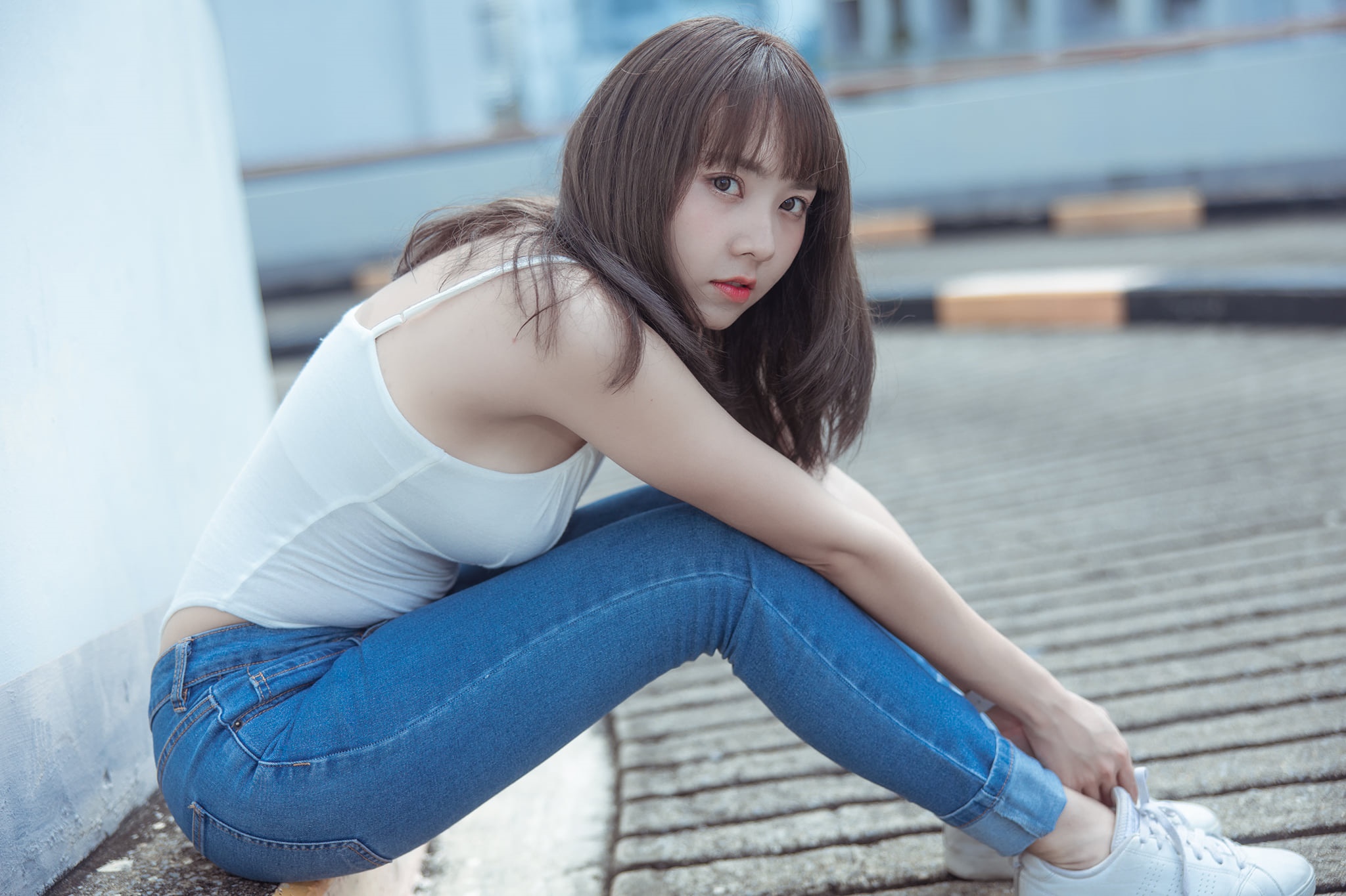 Asian girl in white tank top and jeans sitting outdoors HD Wallpaper