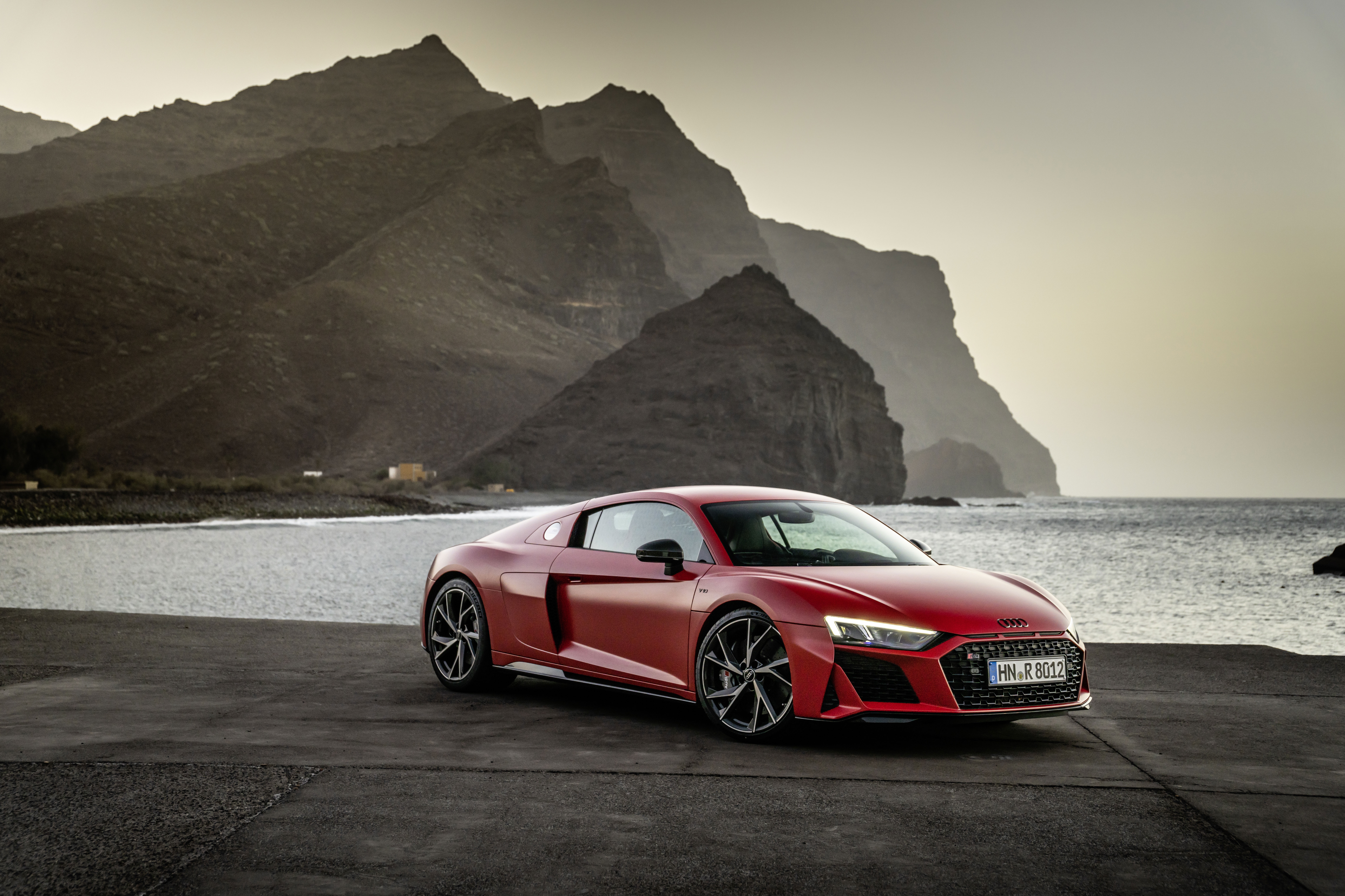 Red Audi R8 V10 parked by the sea with mountains HD Wallpaper