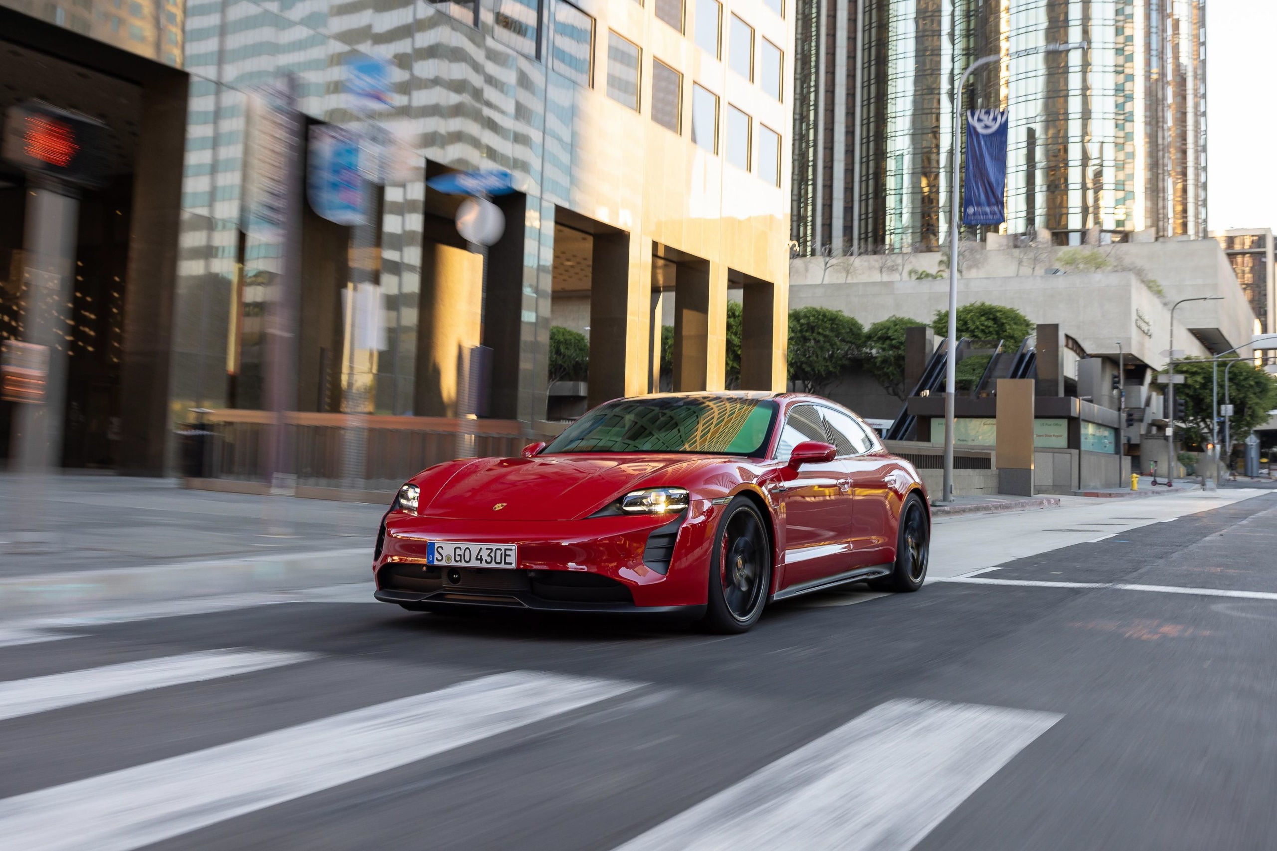 Red Porsche Taycan GTS Sport Turismo driving on city street HD Wallpaper