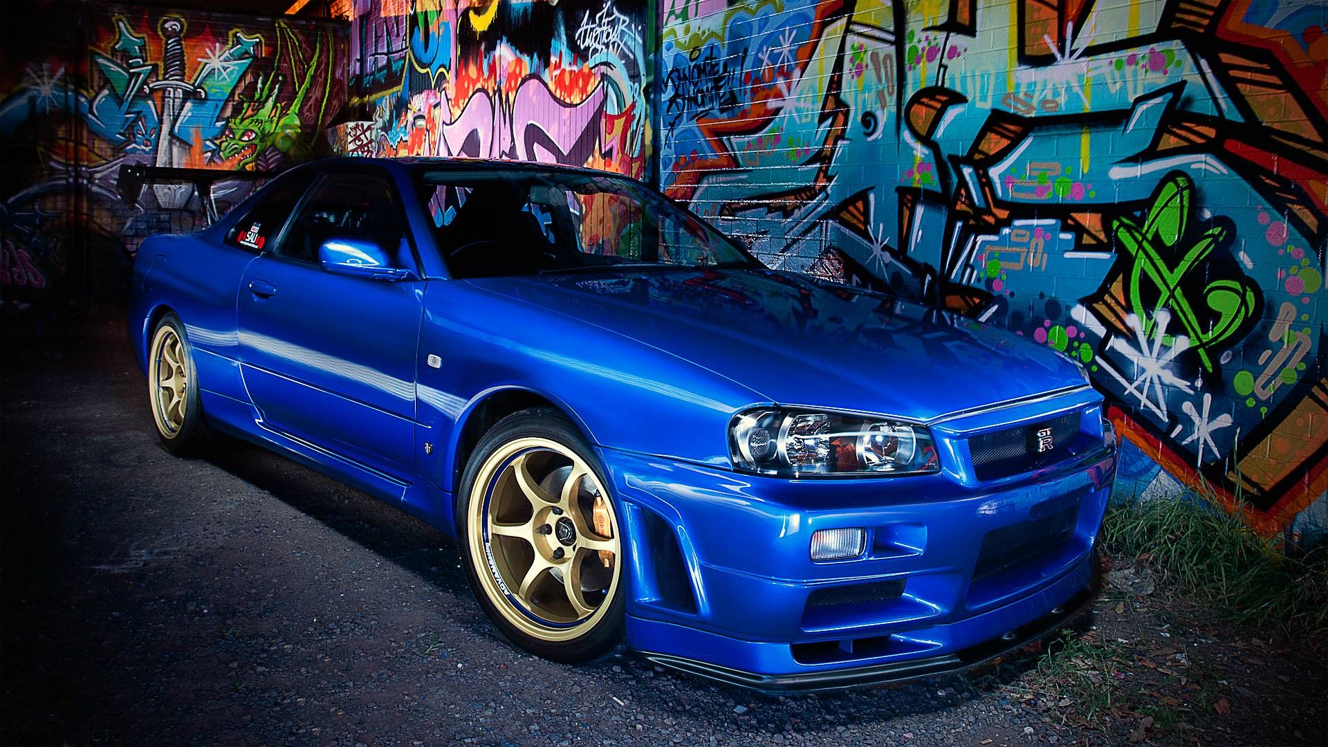 Blue Nissan Skyline R34 parked in front of graffiti HD Wallpaper