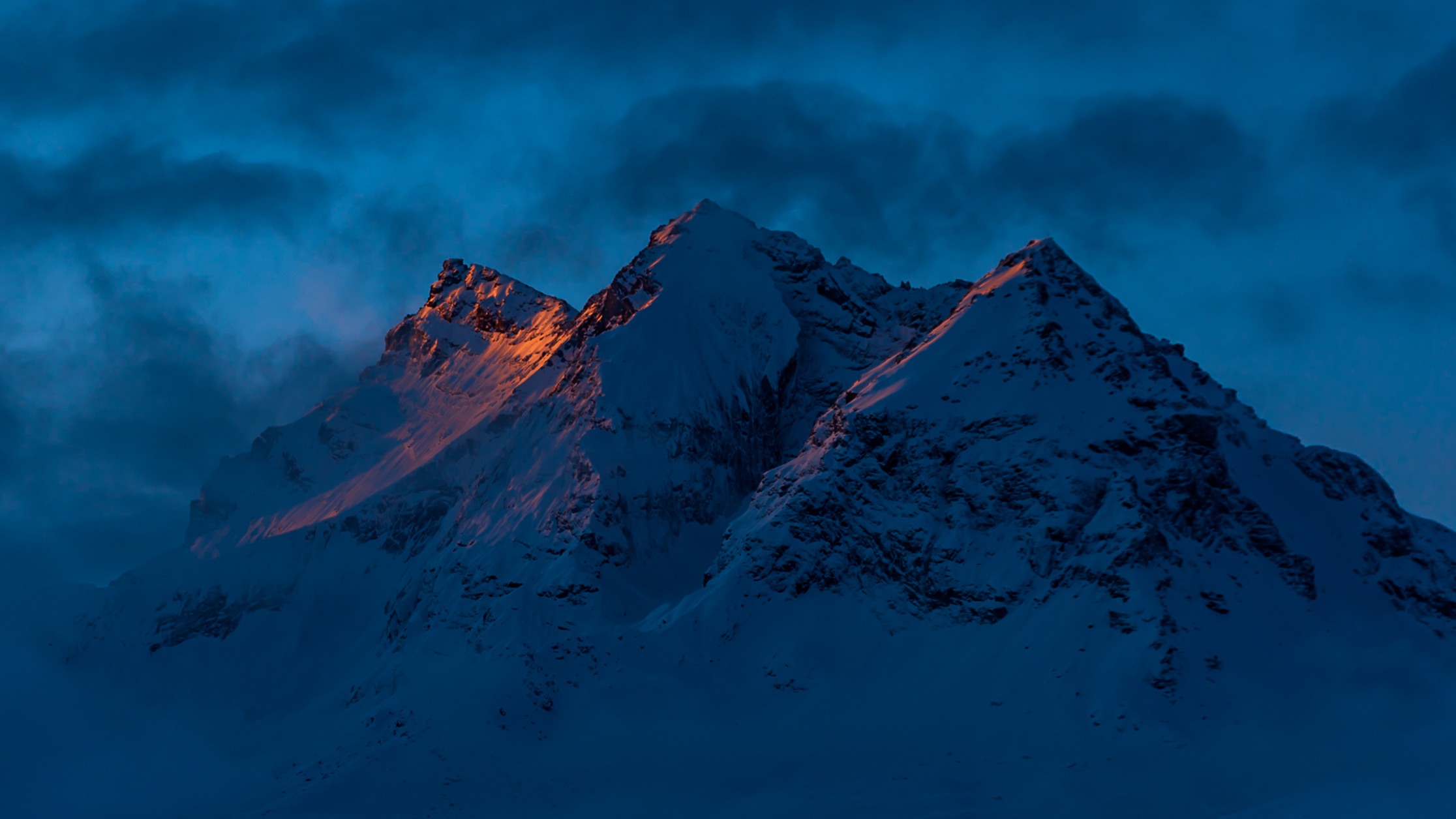 Snowy mountains catching the last light of sunset HD Wallpaper