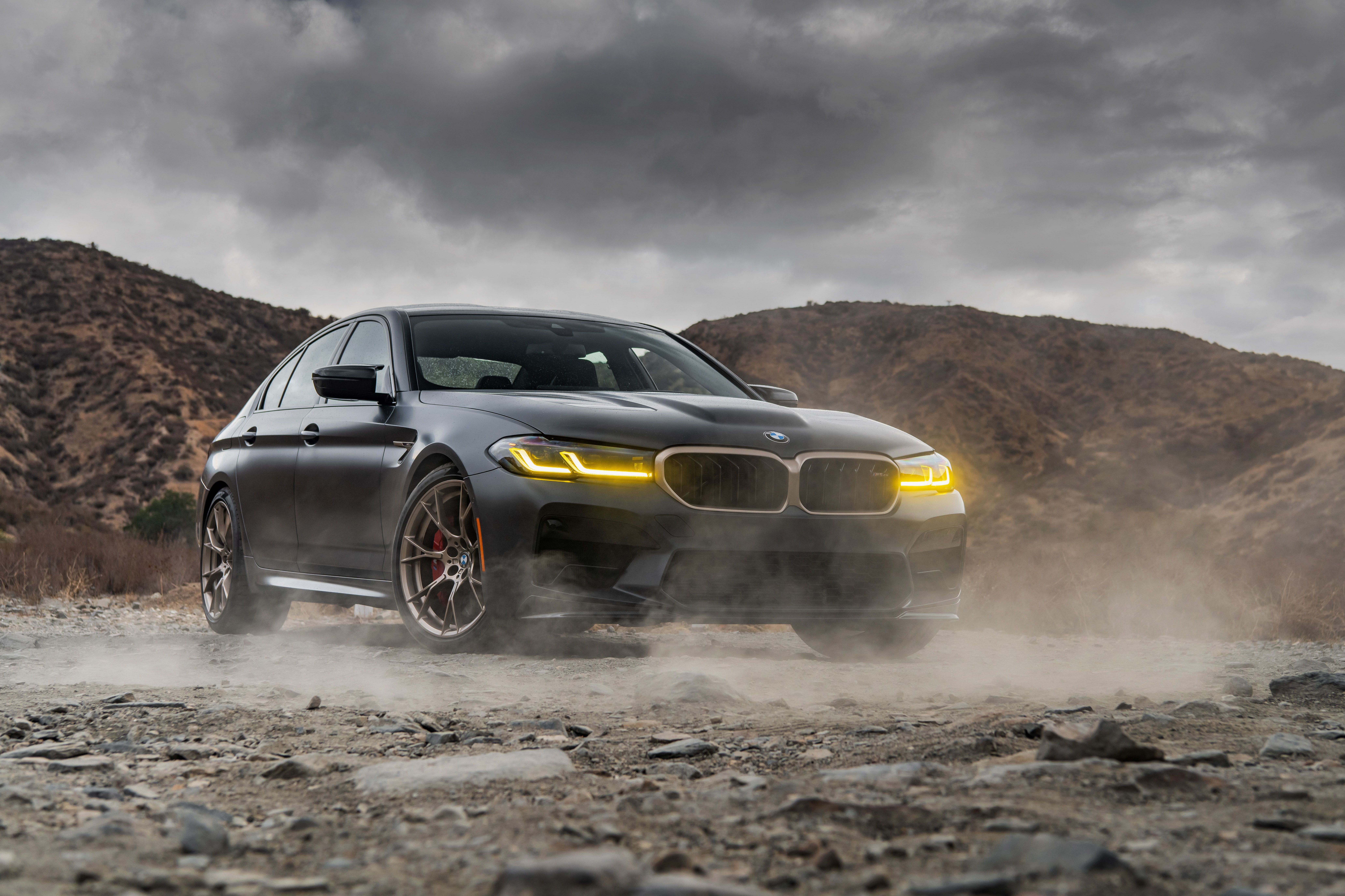 Dark BMW M5 CS on a dusty dirt road HD Wallpaper