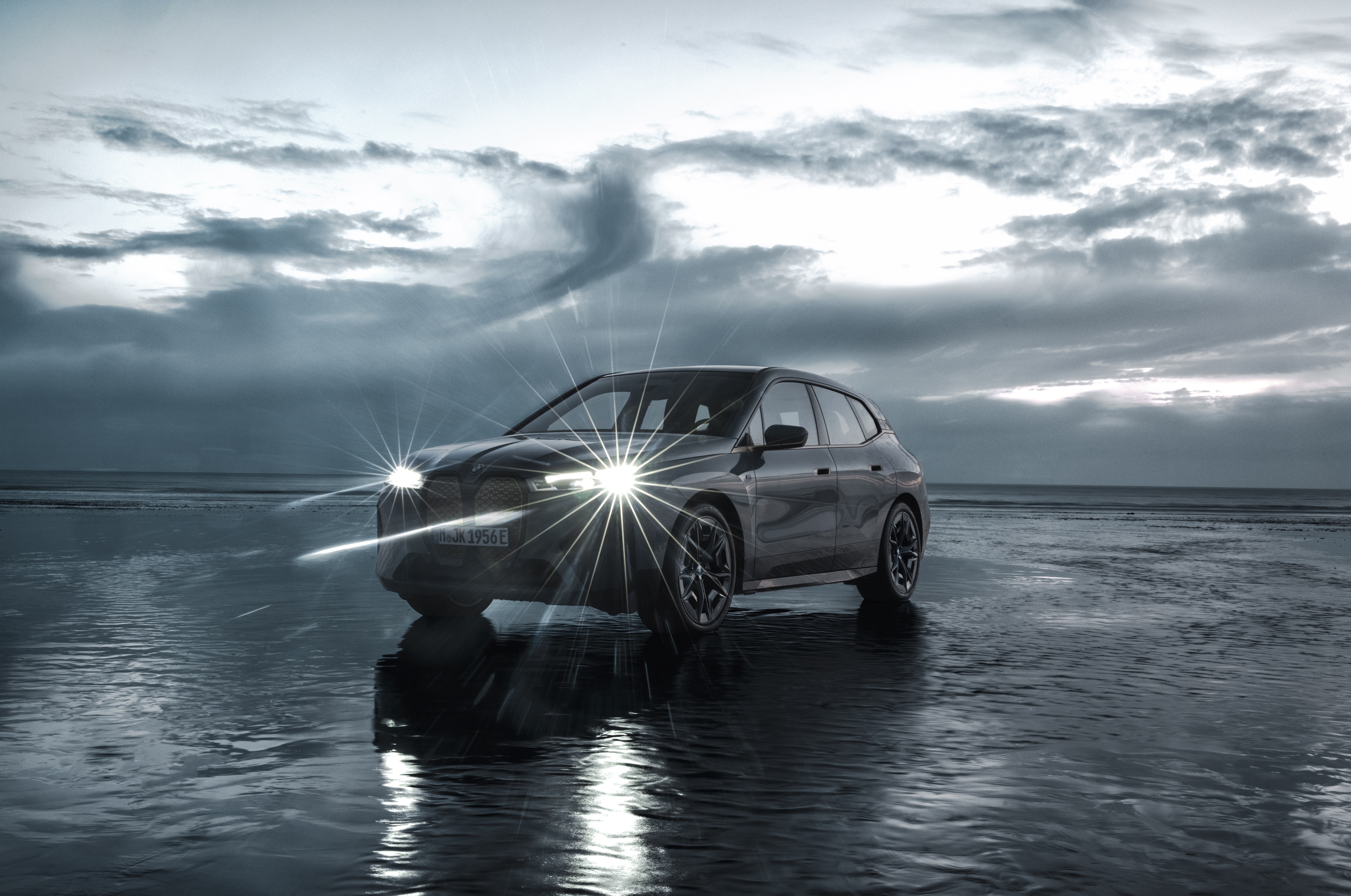 BMW iX M60 electric SUV on a wet beach HD Wallpaper
