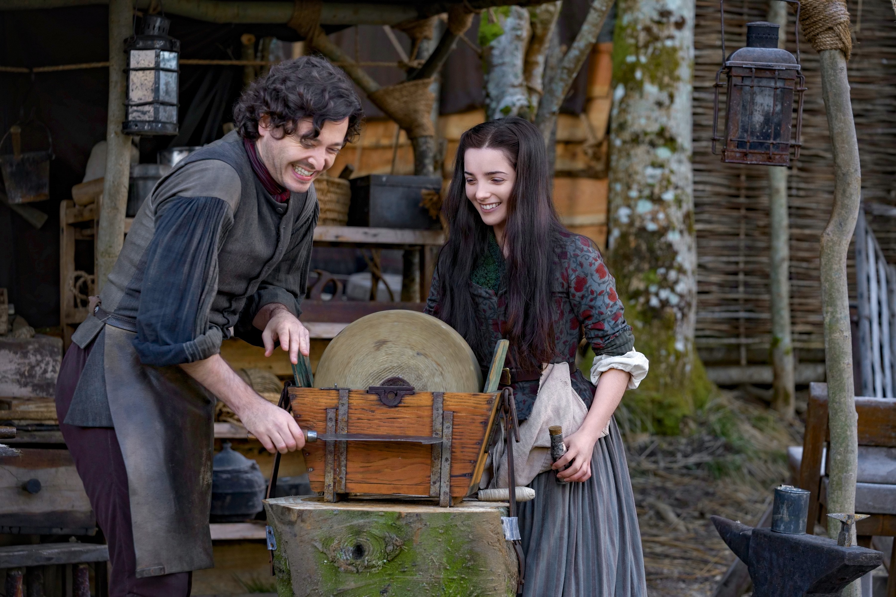 Man and woman sharpening a tool at a grindstone HD Wallpaper