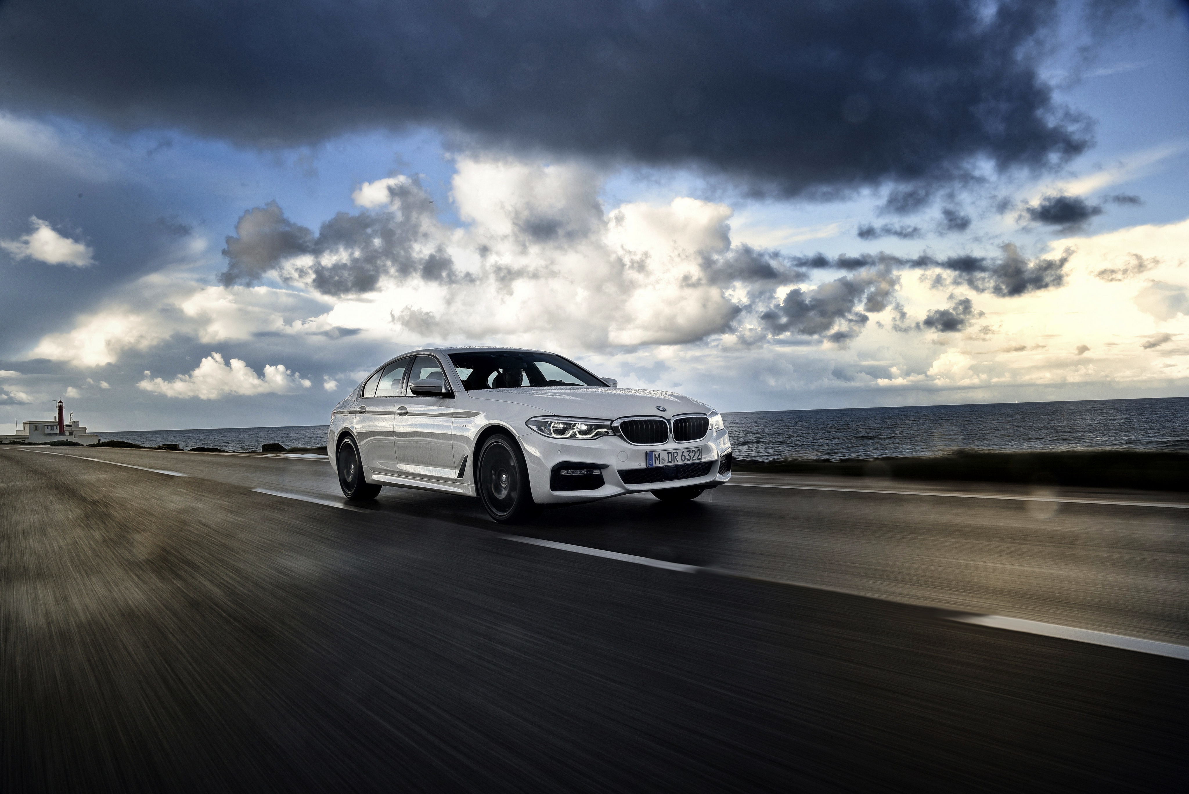 White BMW 5 Series driving on coastal road HD Wallpaper